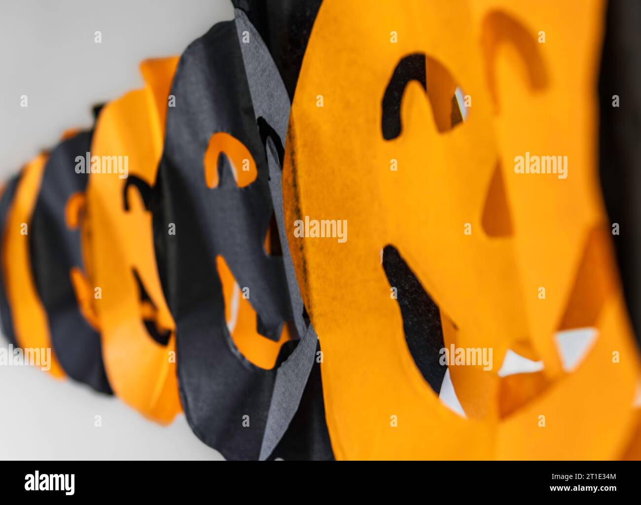 Papierkette aus orangefarbenen und schwarzen Kürbisgesichtern Stockfoto