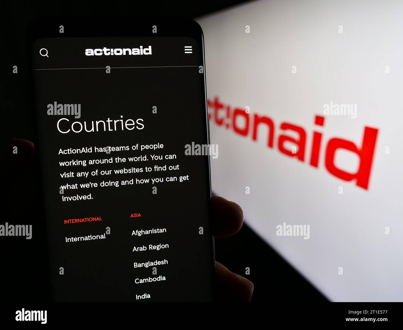 Person mit Smartphone und Webseite der internationalen Wohltätigkeitsorganisation ActionAid vor dem Logo. Konzentrieren Sie sich auf die Mitte des Telefondisplays. Stockfoto