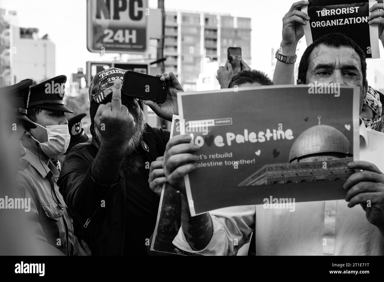 Tokio, Japan. Oktober 2023. Ein Demonstrant mit Trump 2024-Hut flippt bei einer propalästinensischen Kundgebung hinter einem Mann mit einem Schild, der für Frieden und Versöhnung eintritt, von der Presse ab. Mitglieder der islamischen Gemeinschaft in Japan und japanische Unterstützer protestieren vor der israelischen Botschaft in Solidarität mit Palästina und gegen Israel der Krieg im Gazastreifen, nachdem die militante Gruppe der Hamas einen Bodenangriff auf Israel gestartet hatte. Israel und die IDF haben begonnen, Truppenansammlungen an der Grenze anzuhäufen und den Gazastreifen mit der Blockierung von Nahrungsmitteln, Strom und Wasser zu belegen. (Kreditbild: Stockfoto