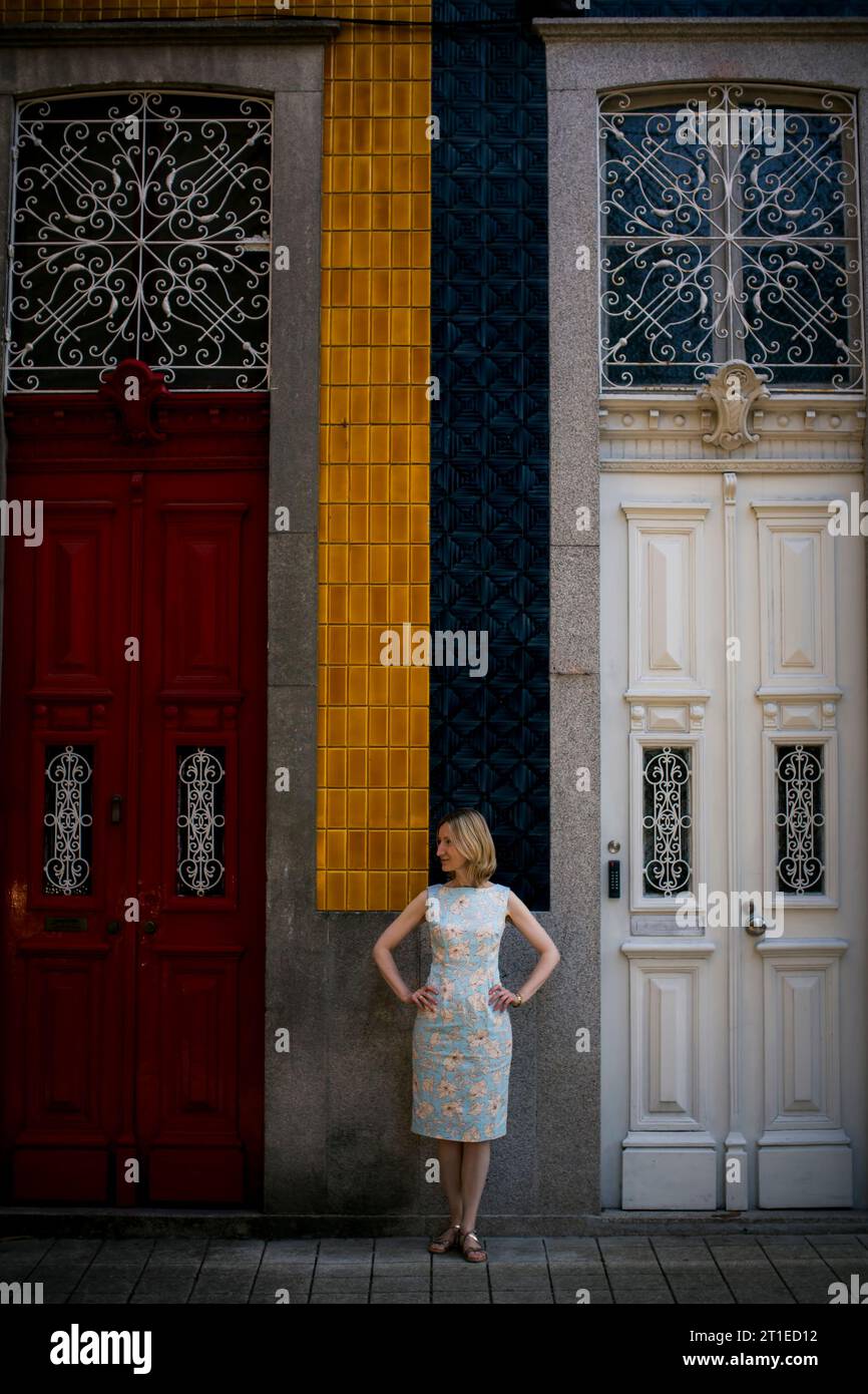 Eine Frau steht vor einem traditionellen Haus mit hohen Türen in Porto, Portugal. Stockfoto