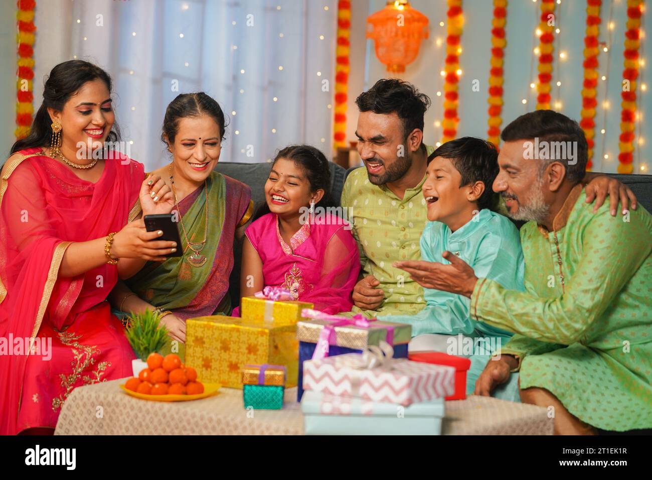 Gruppe glücklicher indischer gemeinsamer Familie, die ihr Handy während der diwali-Festveranstaltung sieht - Konzept emotionaler Wiedervereinigung, Beziehungsbindung Stockfoto