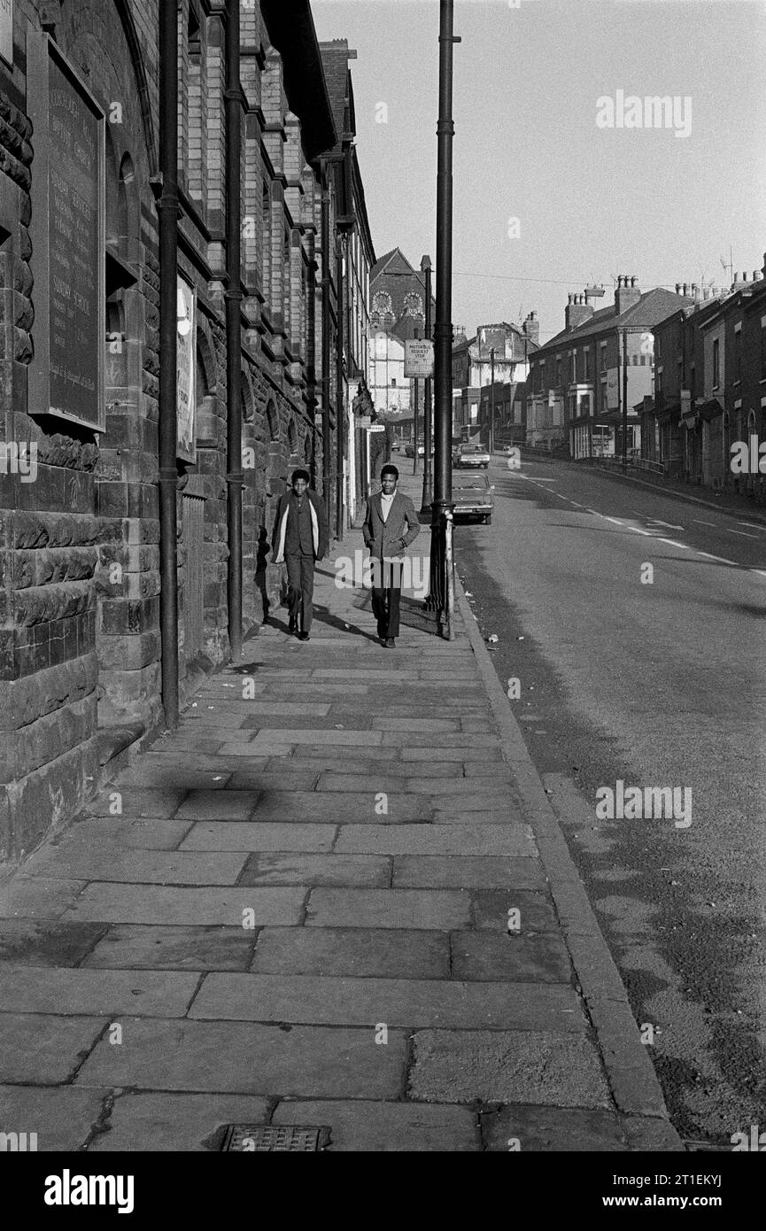 Zwei klug gekleidete junge Männer, die an der Woodborough Road Baptist Church vorbeilaufen, während der Slumräumung und der Abriss von St. Ann's, Nottingham. 1969-1972 Stockfoto