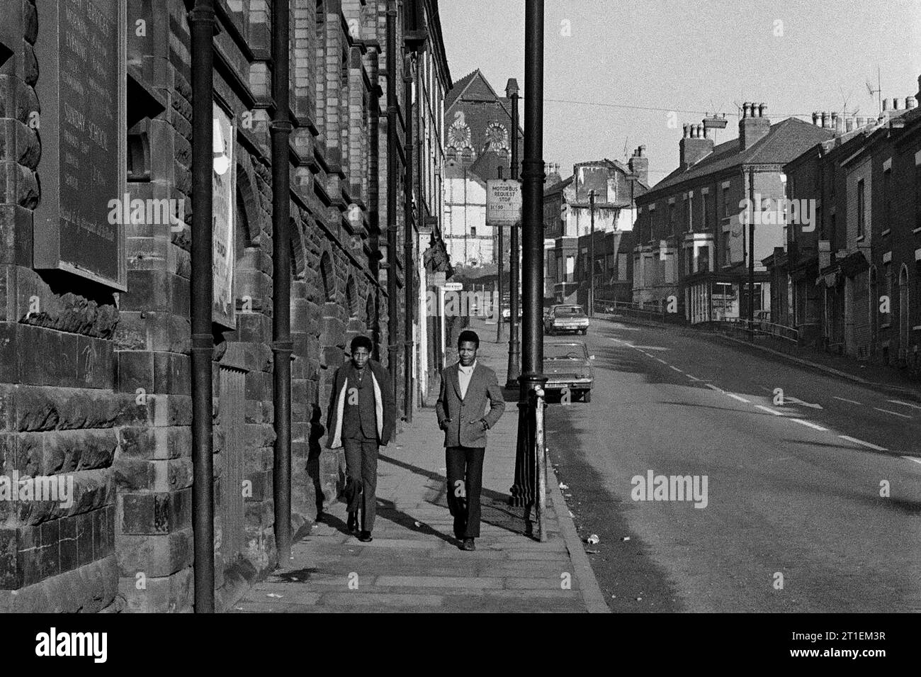 Zwei klug gekleidete junge Männer, die an der Woodborough Road Baptist Church vorbeilaufen, während der Slumräumung und der Abriss von St. Ann's, Nottingham. 1969-1972 Stockfoto