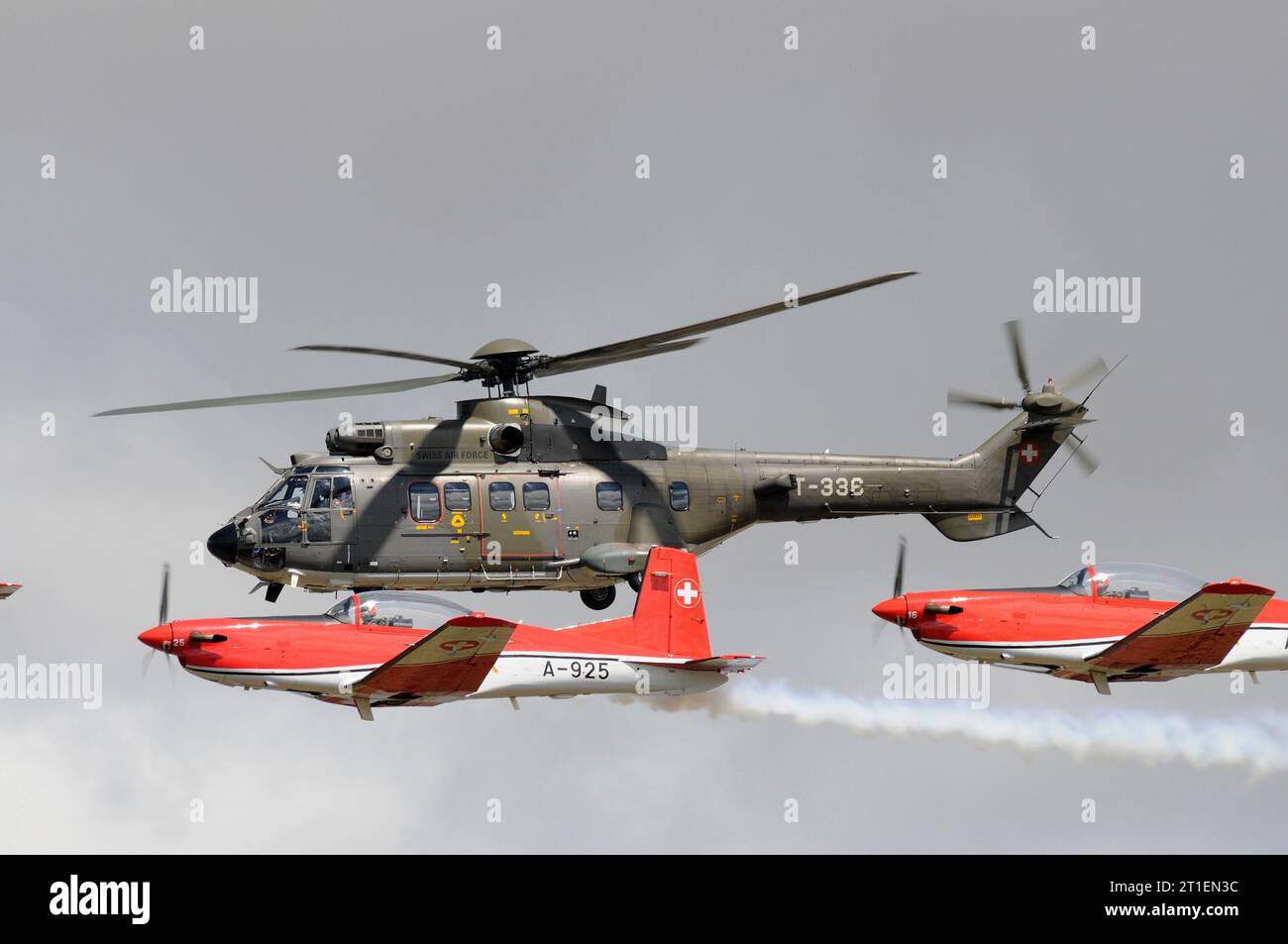 Schweizer Air Force PC-7 Team (9x NCPC-7 Flugzeug) fliegt in Formation mit einem 'Super Puma' auf der RIAT 2015. Stockfoto