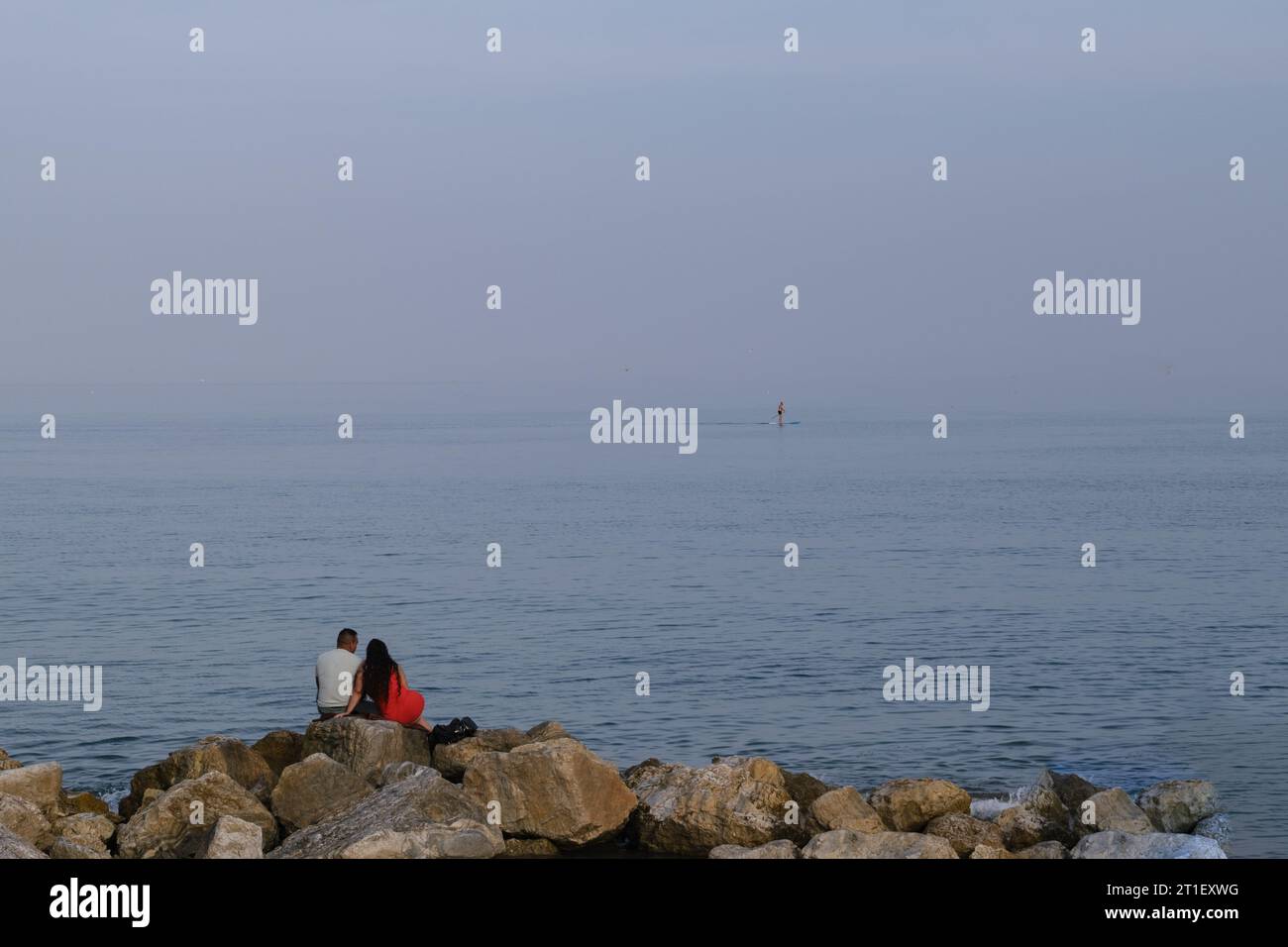 Die Promenade von Malaga, ein Paar, das auf den Felsen des Wellenbrechers sitzt, in den Horizont blickt, verliebt Stockfoto