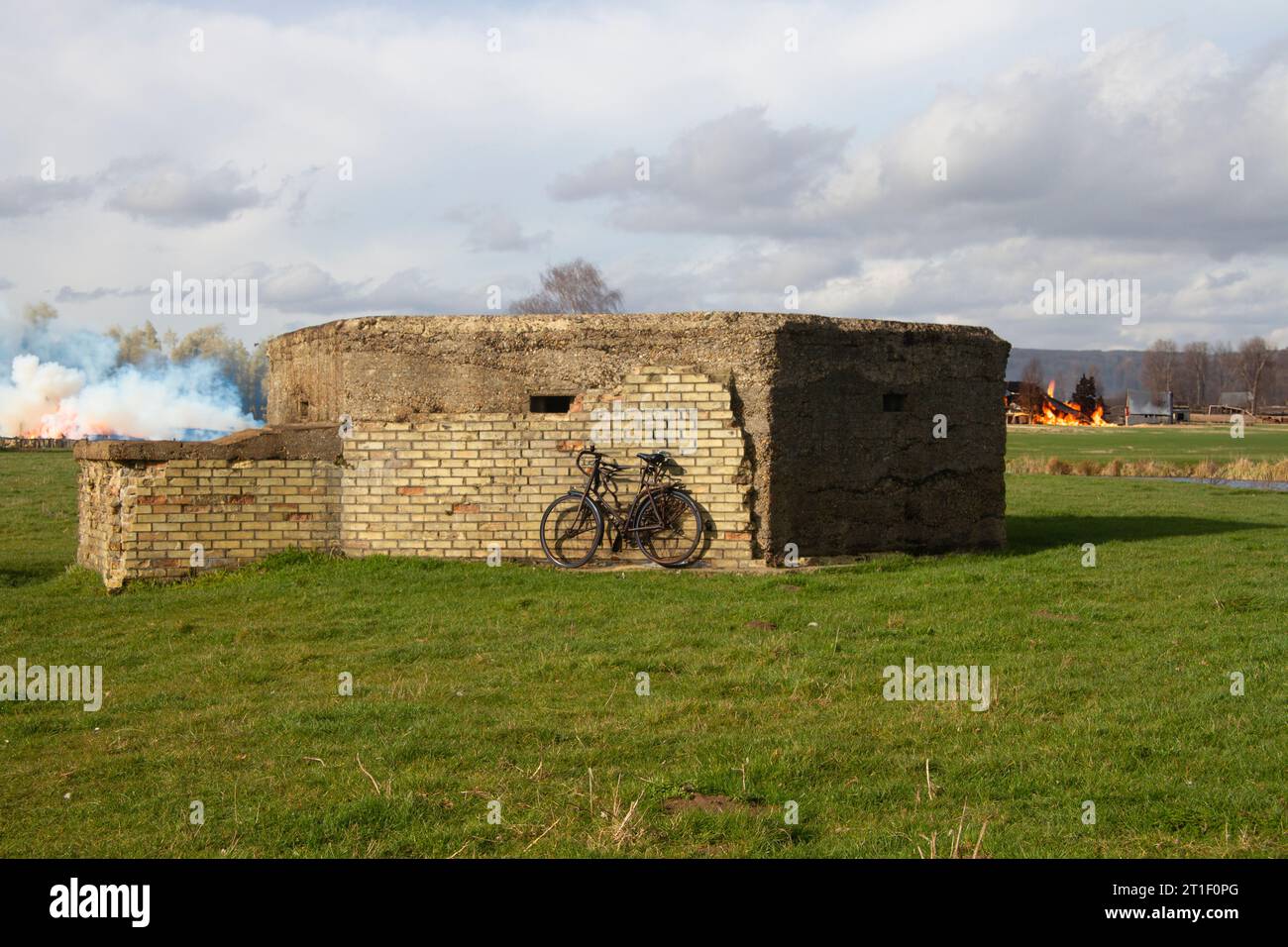 Aus Ziegeln gebauter Luftschutzbunker aus dem Zweiten Weltkrieg in meadowlands, davor ein altes Fahrrad parkte und in der Ferne gebrannte Gebäude Stockfoto
