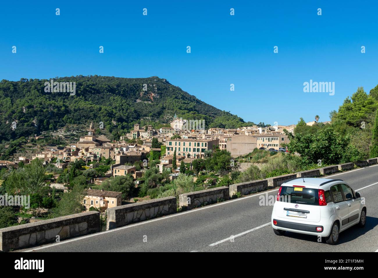 Weißes Auto auf der Straße, die die hübsche Stadt Valldemossa (Mallorca, Spanien) in der Sierra de Tramuntana erreicht Stockfoto