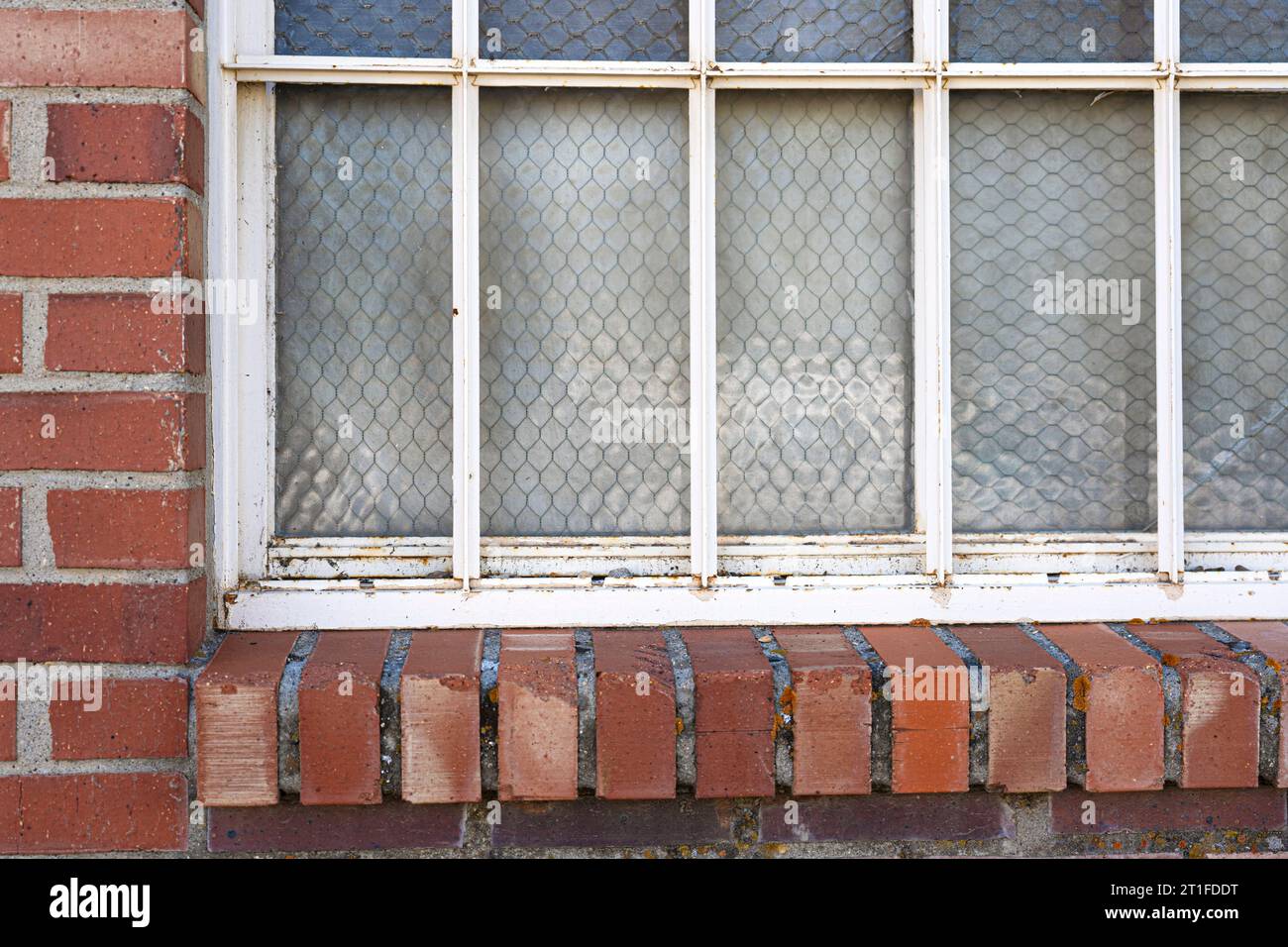 Die alte Fensternähe hat ein rotes Backsteinregal oder einen Felsvorsprung. Viele Fensterscheiben haben mattes Glas, um deckend zu machen. Bereit für das Hinzufügen von Regalsitzern. Stockfoto