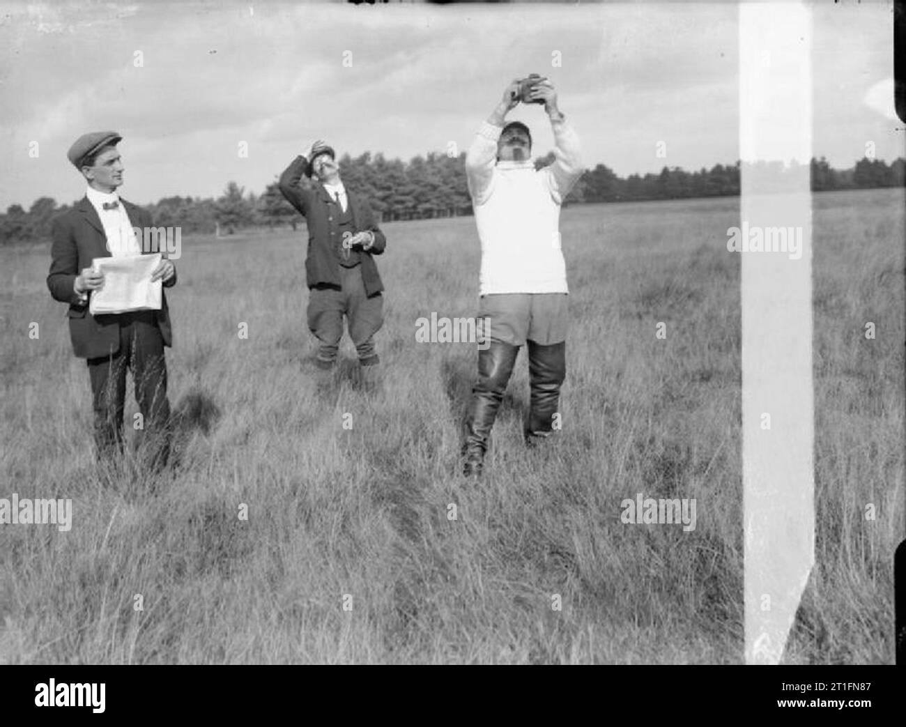 Luftfahrt in Großbritannien vor dem Ersten Weltkrieg Cody und zwei andere stand in einer Wiese möglicherweise die Messung der Windrichtung. Cody Tragen eines weißen Pullover und Oberschenkel Länge Stiefel hält sich eine Art kleinen Gerät. Stockfoto