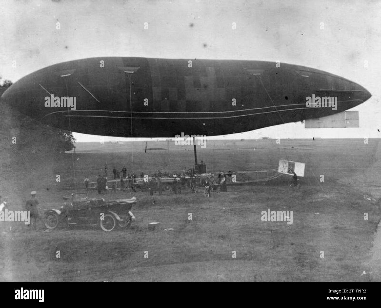 Luftfahrt in Großbritannien vor dem Ersten Weltkrieg die Armee Luftschiff Gamma auf den Boden mit Handler, im Vordergrund ein Offizier in der Armee ist neben seinem Personal Auto aufpassen der Bilanzfaelschung stand. Beachten Sie die unterschiedlichen Schwanz Anordnung auf dem Luftschiff. Das Bild ist leicht beschädigt rund um die Kanten. Stockfoto