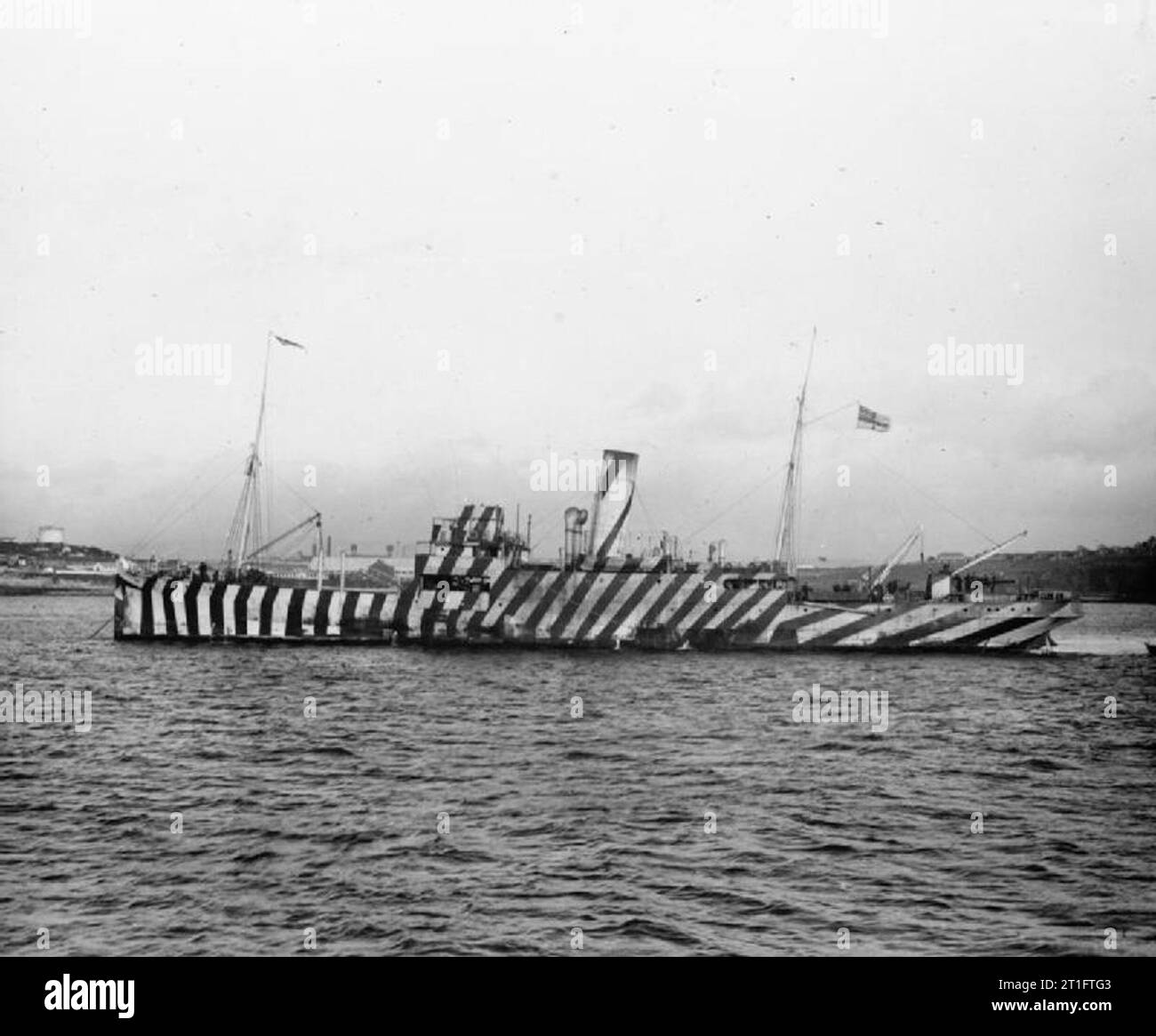 IWM-BILDUNTERSCHRIFT : das 'Q'-Schiff HMS UNTER DEM FLÜGEL, vor Anker mit freigelegten Geschützen und gestreiftem Blendschutz. Stockfoto