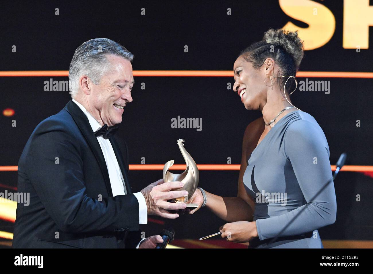 Leipzig, Deutschland. Oktober 2023. Eishockeytrainer Harold Kreis (l) erhält die Trophäe in der Sportkategorie von Moderatorin Mariama Jamanka bei der Medienpreisverleihung „Goldene Henne“. Der Publikumspreis wird zum 29. Mal auf einer TV-Gala in Leipzig verliehen. Quelle: Hendrik Schmidt/dpa/Alamy Live News Stockfoto