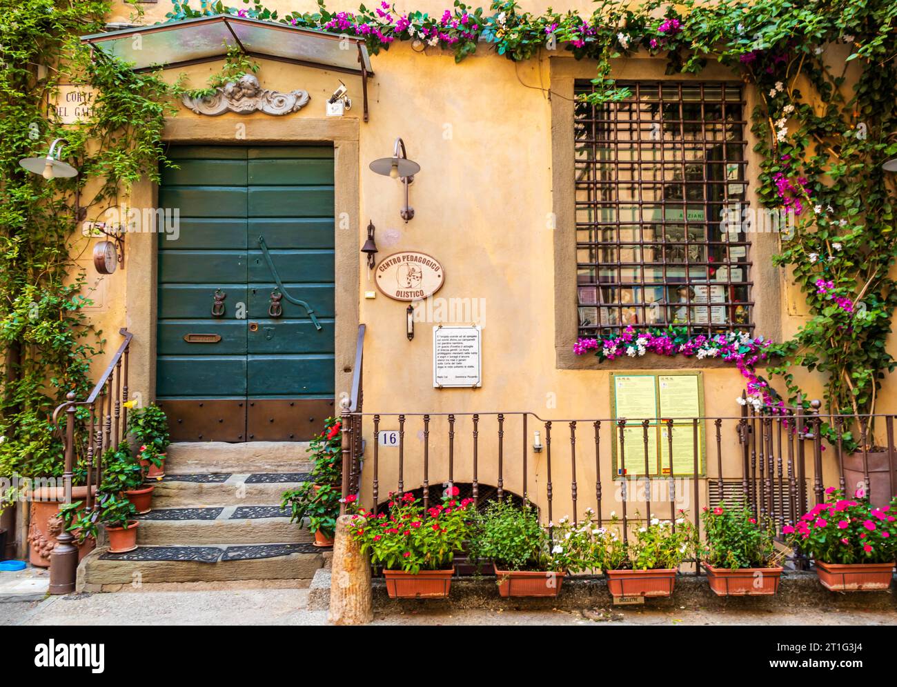 Bezaubernde Fassade des Gebäudes in Lucca, Italien. Das Centro Pedacogico bietet Programme für Kinder. Blumen um das Fenster und die grüne Tür. Stockfoto