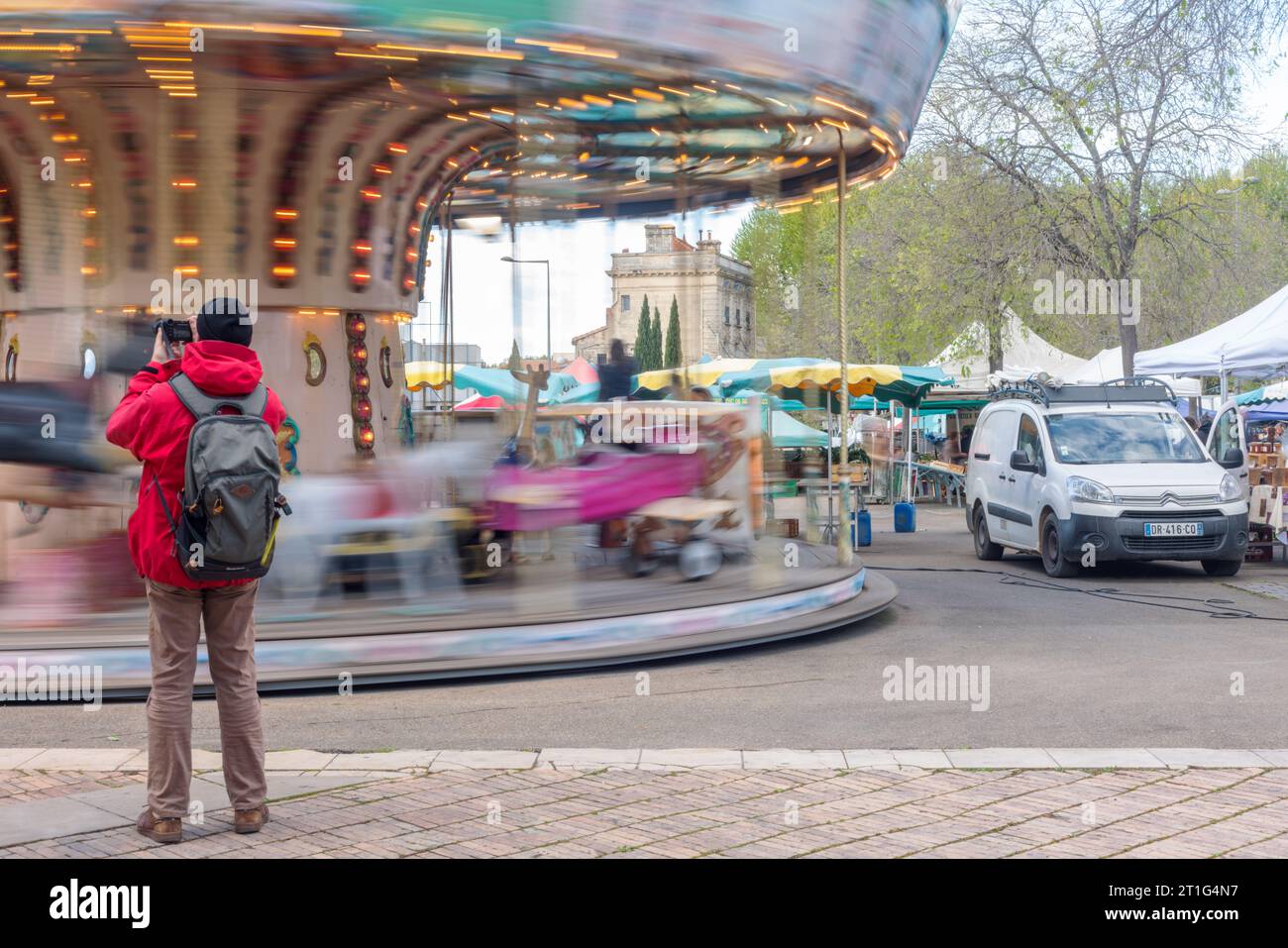 Ein Tourist fotografiert ein Karussell in Aktion auf dem Freiluftmarkt Saurday in Arles, Provence, Südfrankreich. Stockfoto