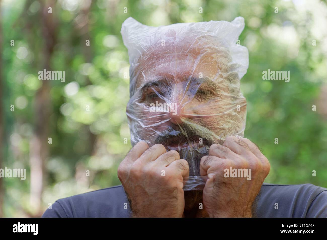 Ein Mann mit einer Plastiktüte auf dem Kopf, der auf dem Land ertrunken ist und das Konzept der Ökologie recycelt Stockfoto