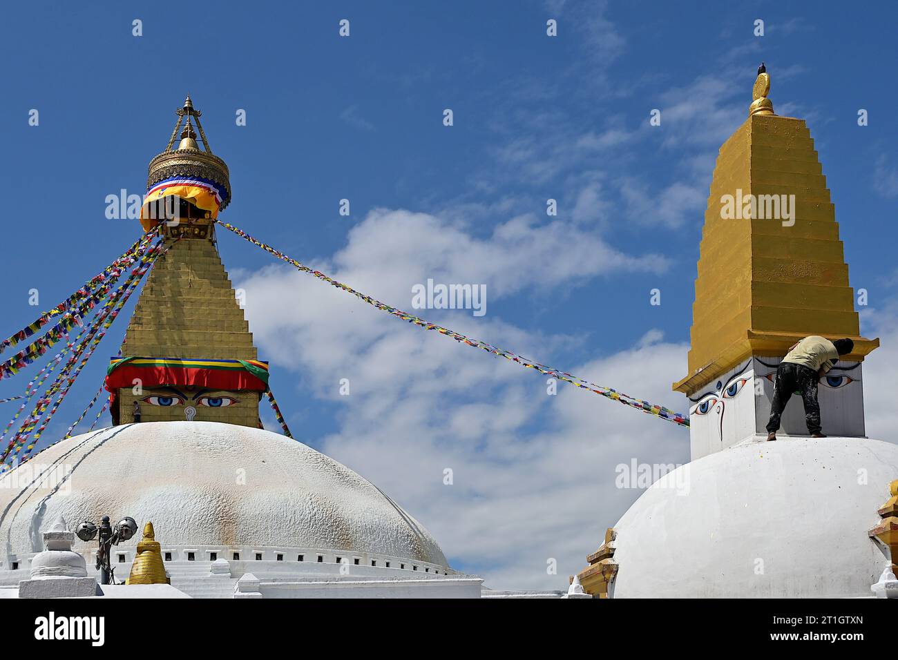 Malte alle sehenden Augen Buddhas, der die vier Himmelsrichtungen überwacht, während ein Arbeiter Farbe auf den Turm einer Stupa aufträgt, Boudhanath, Kathmandu, Nepal Stockfoto