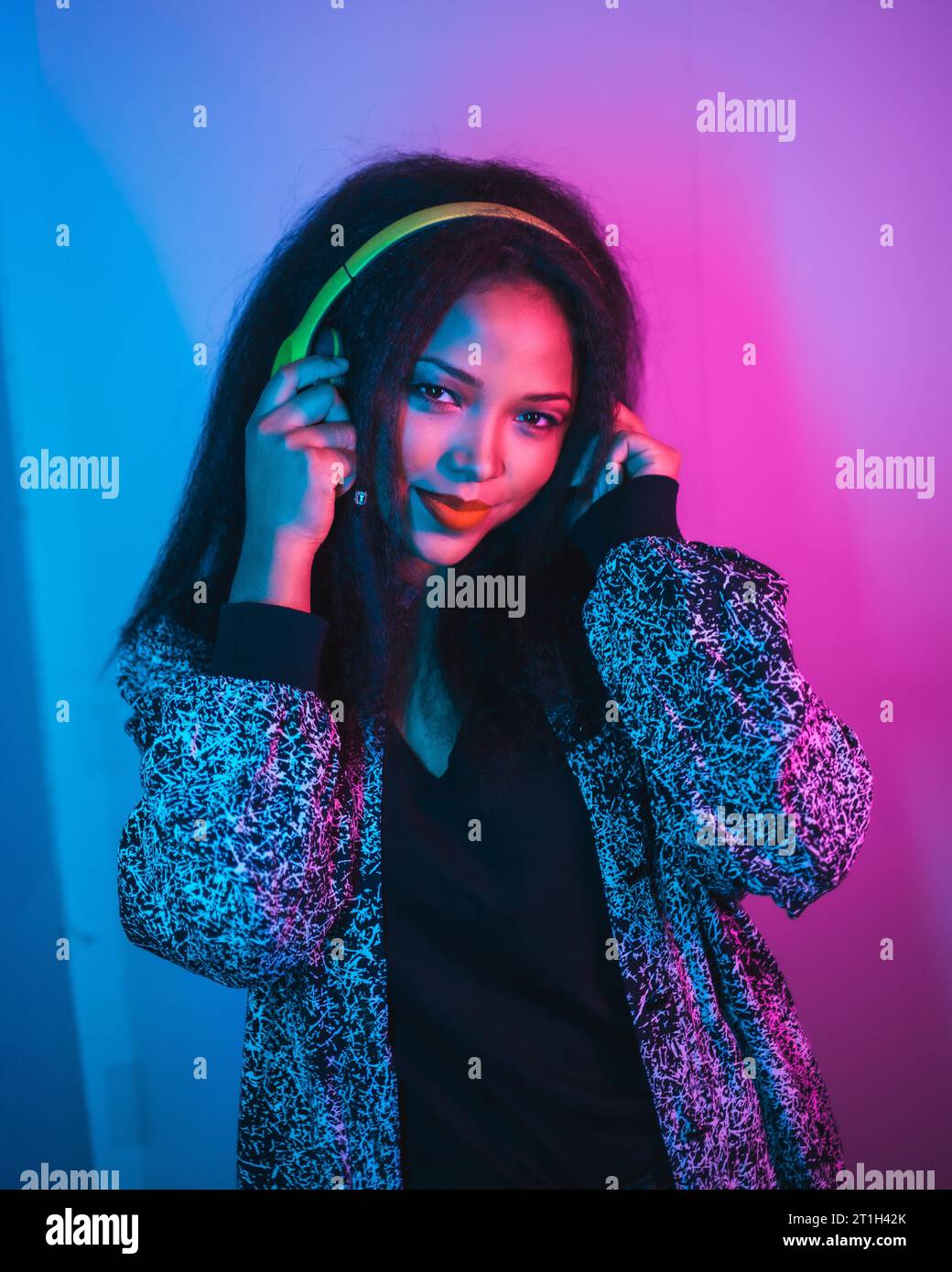 Eine vertikale Nahaufnahme einer aufgeregt kühlen hispanischen Frau genießen Musik mit Kopfhörern und Tanz Stockfoto