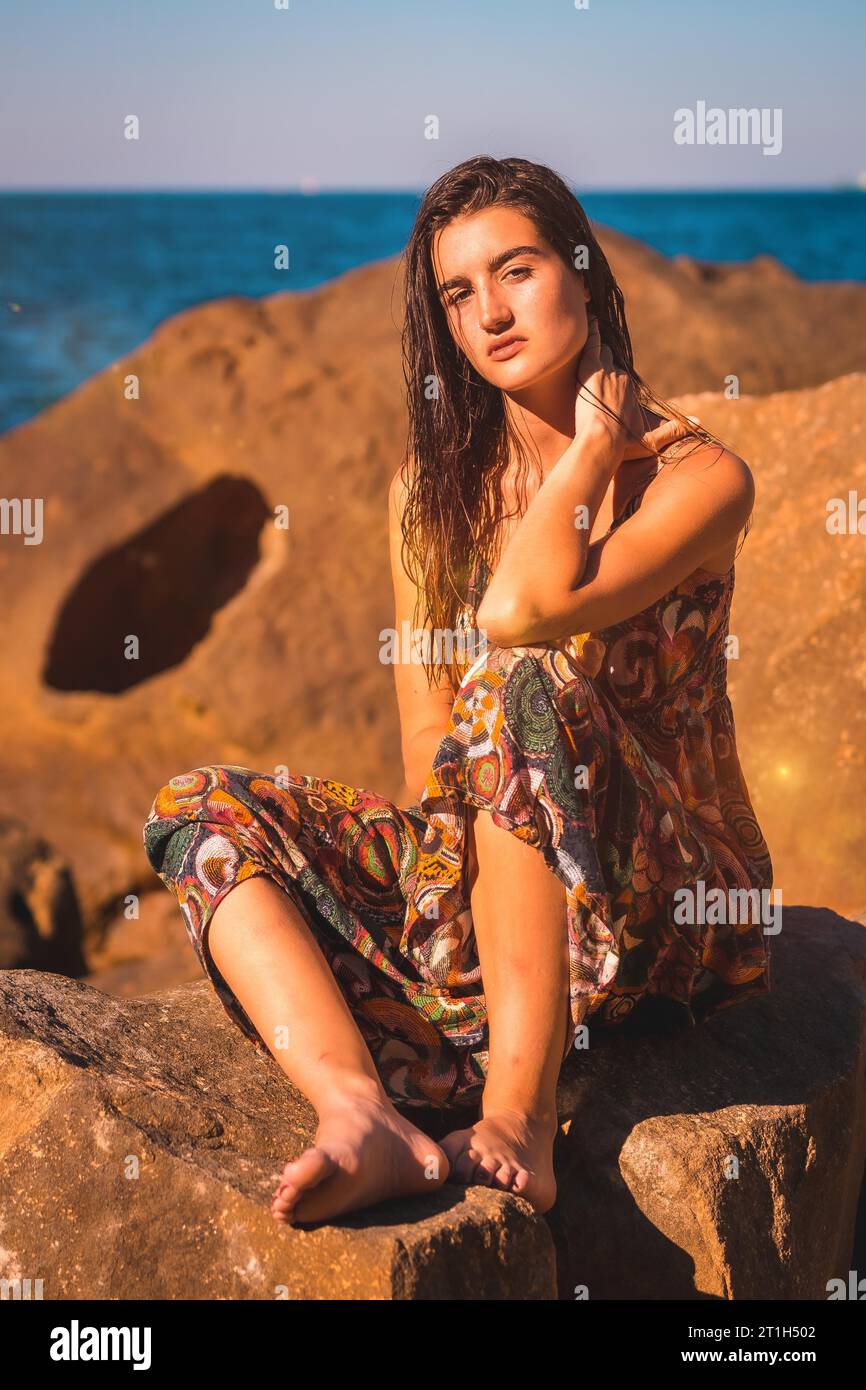 Porträt einer jungen Brünette mit nassen Haaren und einem Blumenkleid am Meer, Sommer-Lifestyle Stockfoto