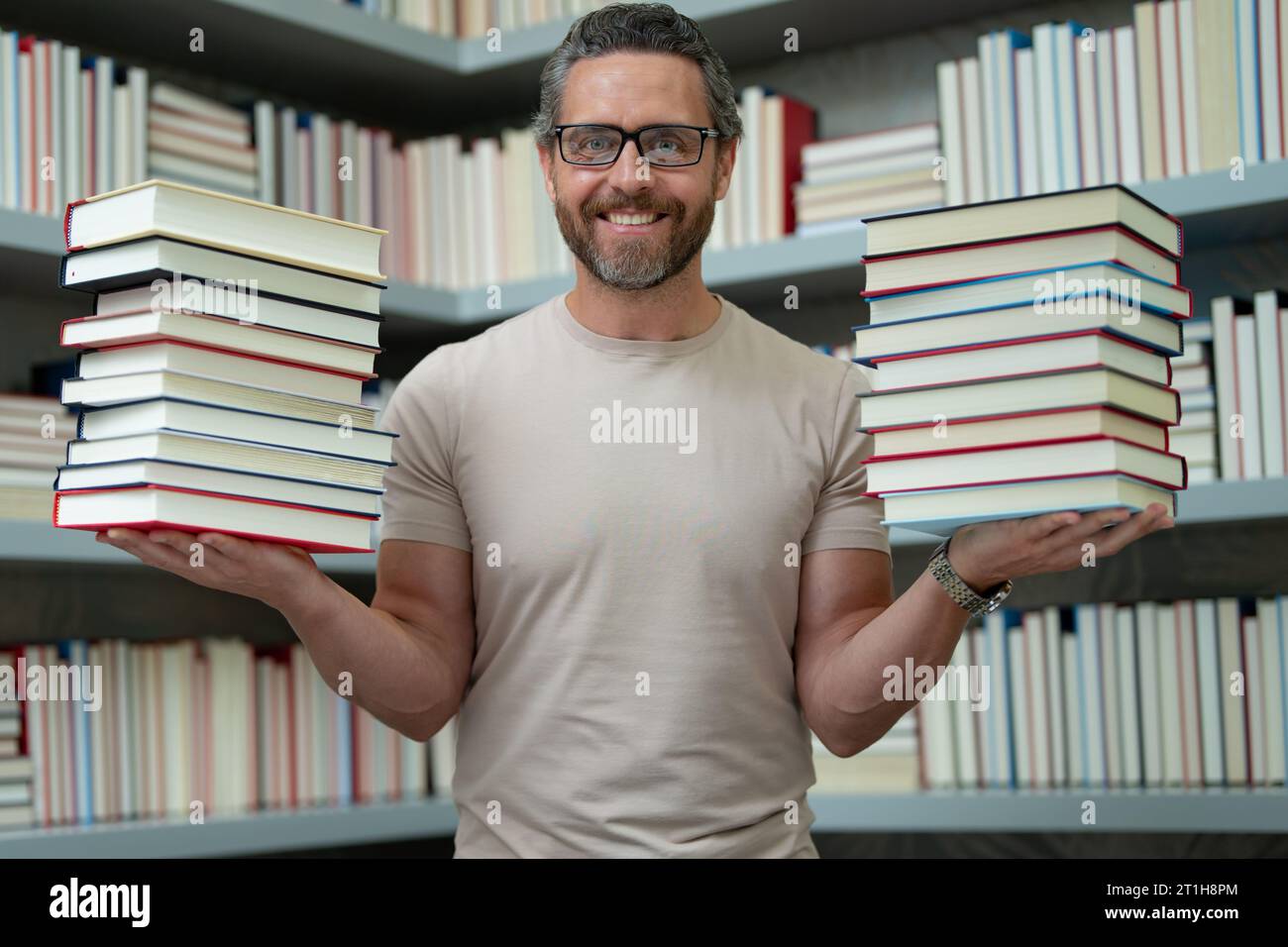 Lehrertag. Guter Lehrer. Tutor im Klassenzimmer. Mann Lehrer mit Büchern im Klassenzimmer. Wissens- und Bildungskonzept. Lustiger Lehrer hält viele Bücher Stockfoto