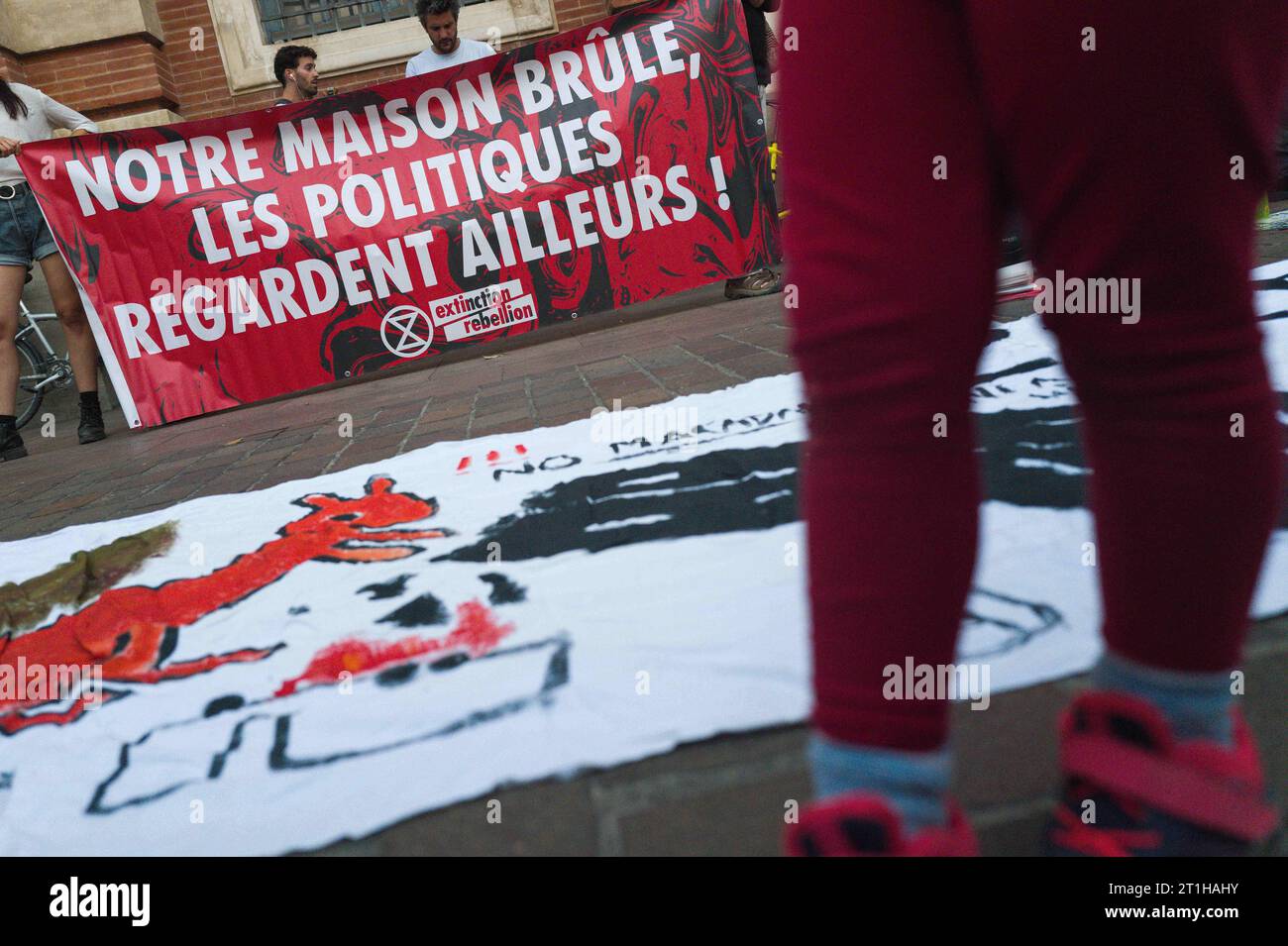 Ein Banner auf dem Boden mit einem No MacAdam Eichhörnchen, und im Hintergrund ein weiteres Banner, unser Haus brennt, Politiker schauen weg! . XR – Extinction Rebellion, mit den Beinen eines Kindes im Vordergrund. A69 Rallye, keine Federung? Kein Ruf nach Ruhe! Für einen sofortigen Stopp der Arbeiten auf der Autobahn A69, Treffen in Toulouse und Paris und vor den Rathäusern in ganz Frankreich. Nach Monaten des Kampfes, wochenlangen Hungerstreiks für 15 Menschen, massiver Mobilisierung von Bürgern, Gewerkschaften und Wissenschaftlern geben Clement Beaune und Carole DELGA nur Krümel nach und verweigern hartnäckig den zugang Stockfoto