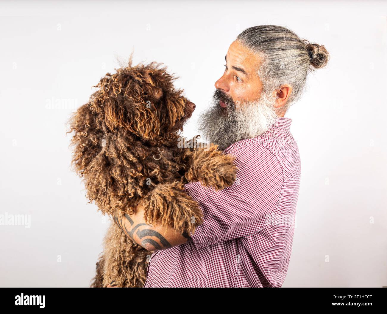 Studio-Porträt eines Hipster-Mannes, der seinen Hund umarmt. Mann spielt mit Hund isoliert auf weißem Hintergrund. Stockfoto