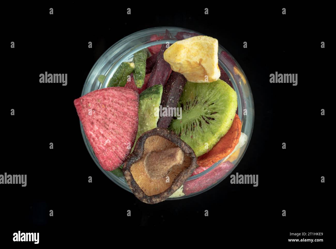 Verschiedene bunte getrocknete Früchte und Gemüse im Glas mit schwarzem Hintergrund. Knuspriges gemischtes Gemüse und Obst, gesunde Snacks, Top View, Spa Stockfoto