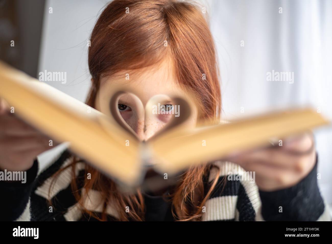 Ein Mädchen hält ein Buch. Seiten in Herzform. Lesen, Wissen, Lernen Stockfoto