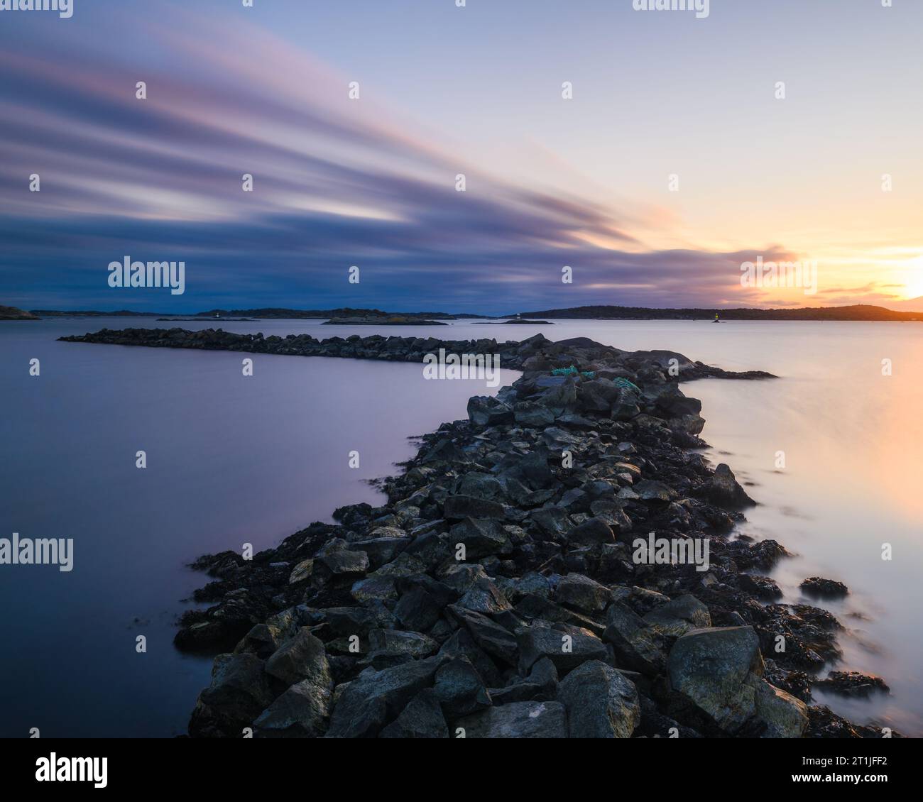 Ruhiger Sonnenuntergang über Göteborgs felsigem Ufer und reflektierendem Wasser. Stockfoto
