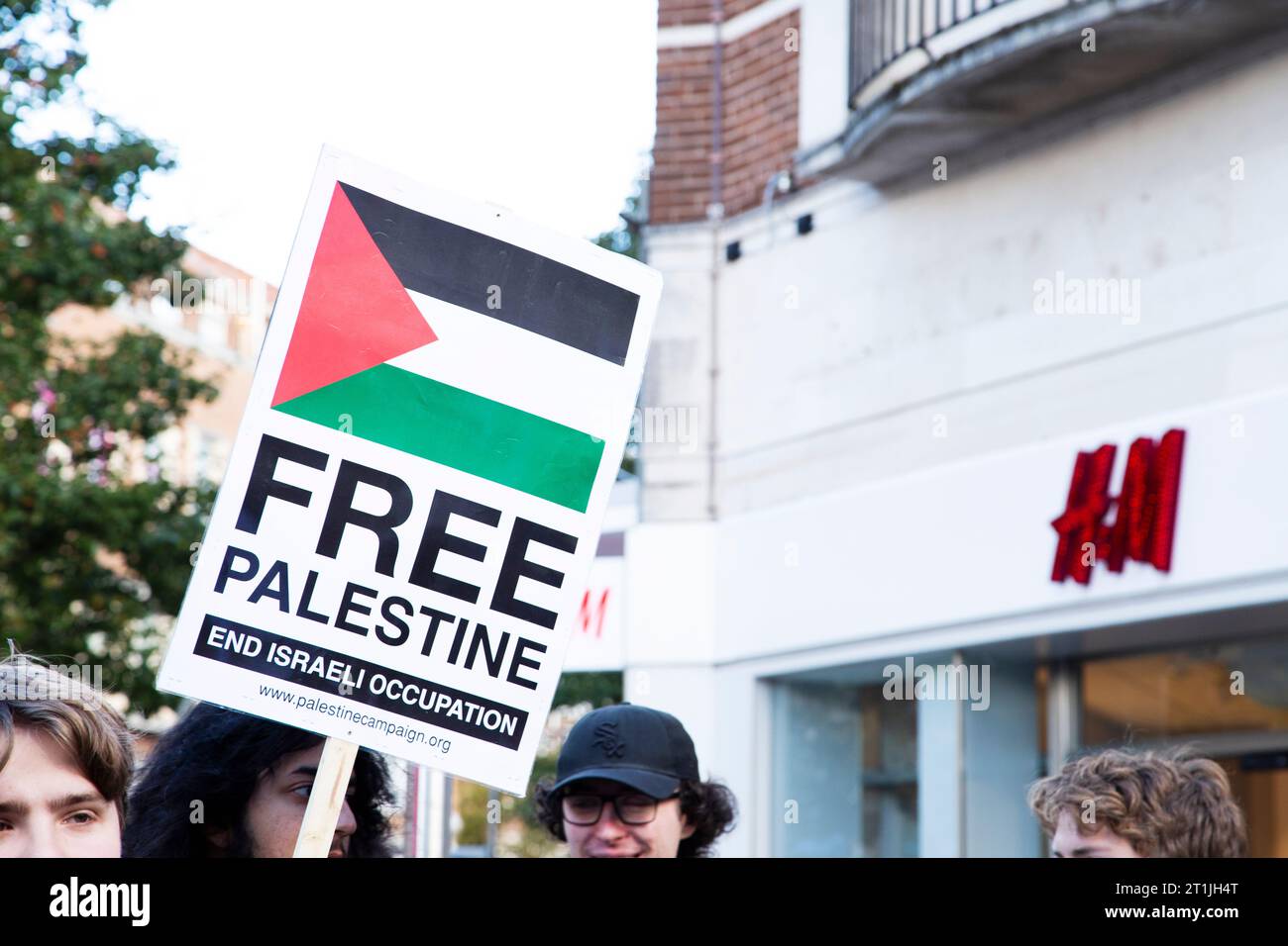 Freier palästinensischer Protest im Stadtzentrum von Exeter - kostenloses palästinensisches Schild neben dem H&M Shop Logo mit Köpfen Stockfoto