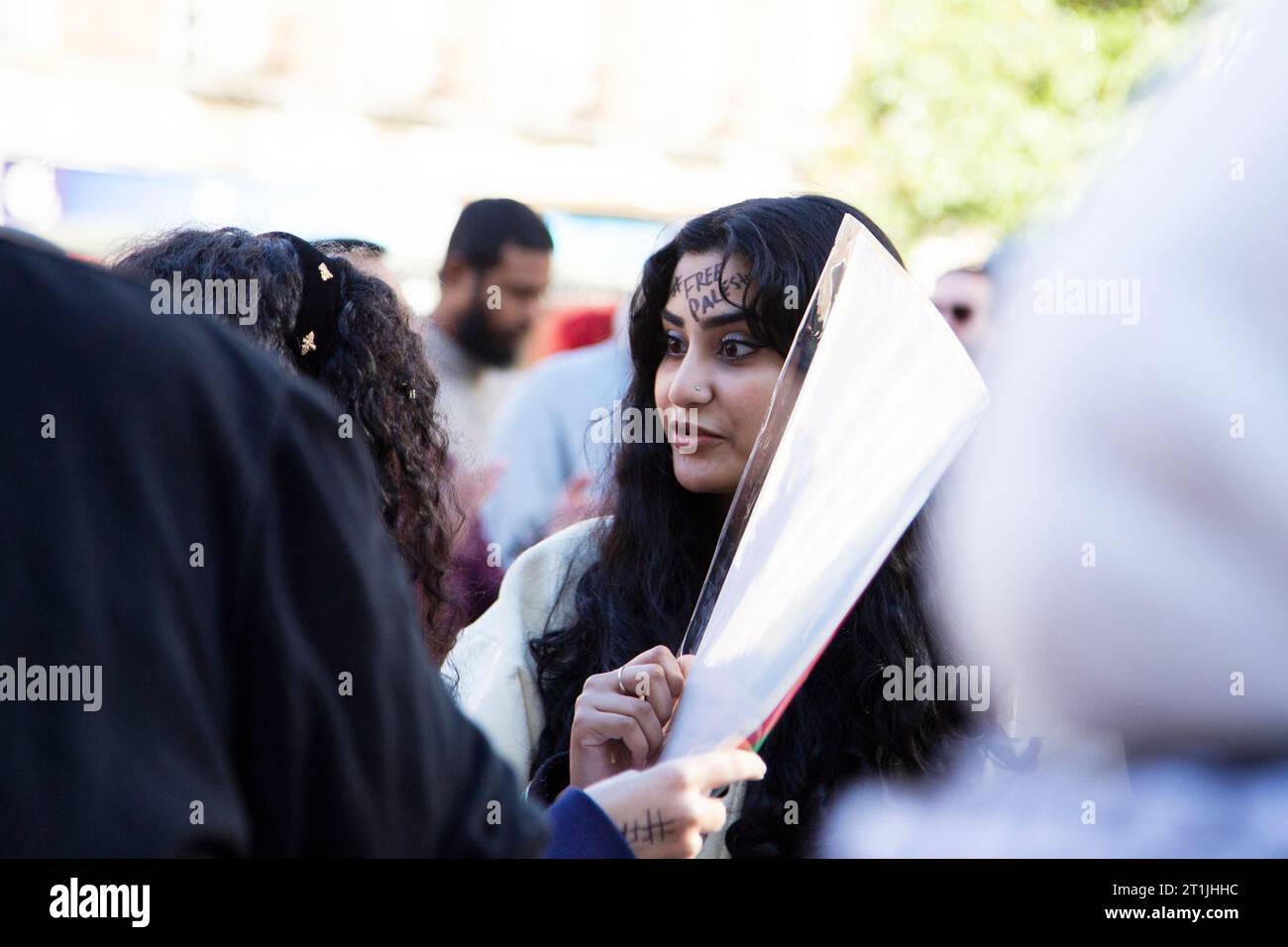 Freier palästinensischer Protest im Stadtzentrum von Exeter - junge palästinensisch aussehende Dame mit schwarzem Hash-Tag '#FREEPALESTINE' auf der Stirn des Gesichts Stockfoto