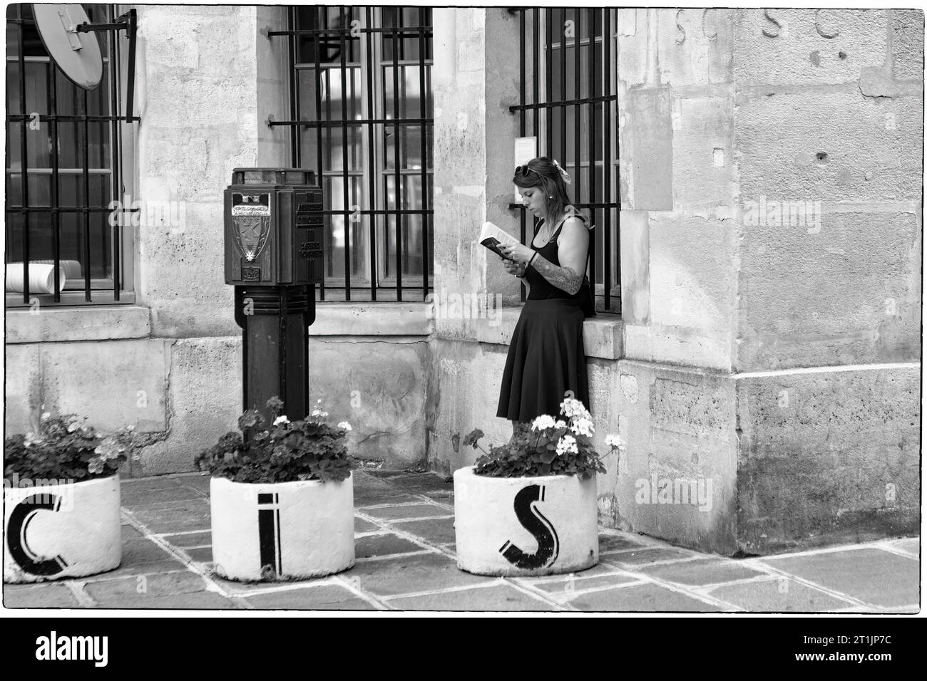 Eine junge Frau liest in einer Ecke des Stadtviertels Le Marais in Paris, Frankreich Stockfoto
