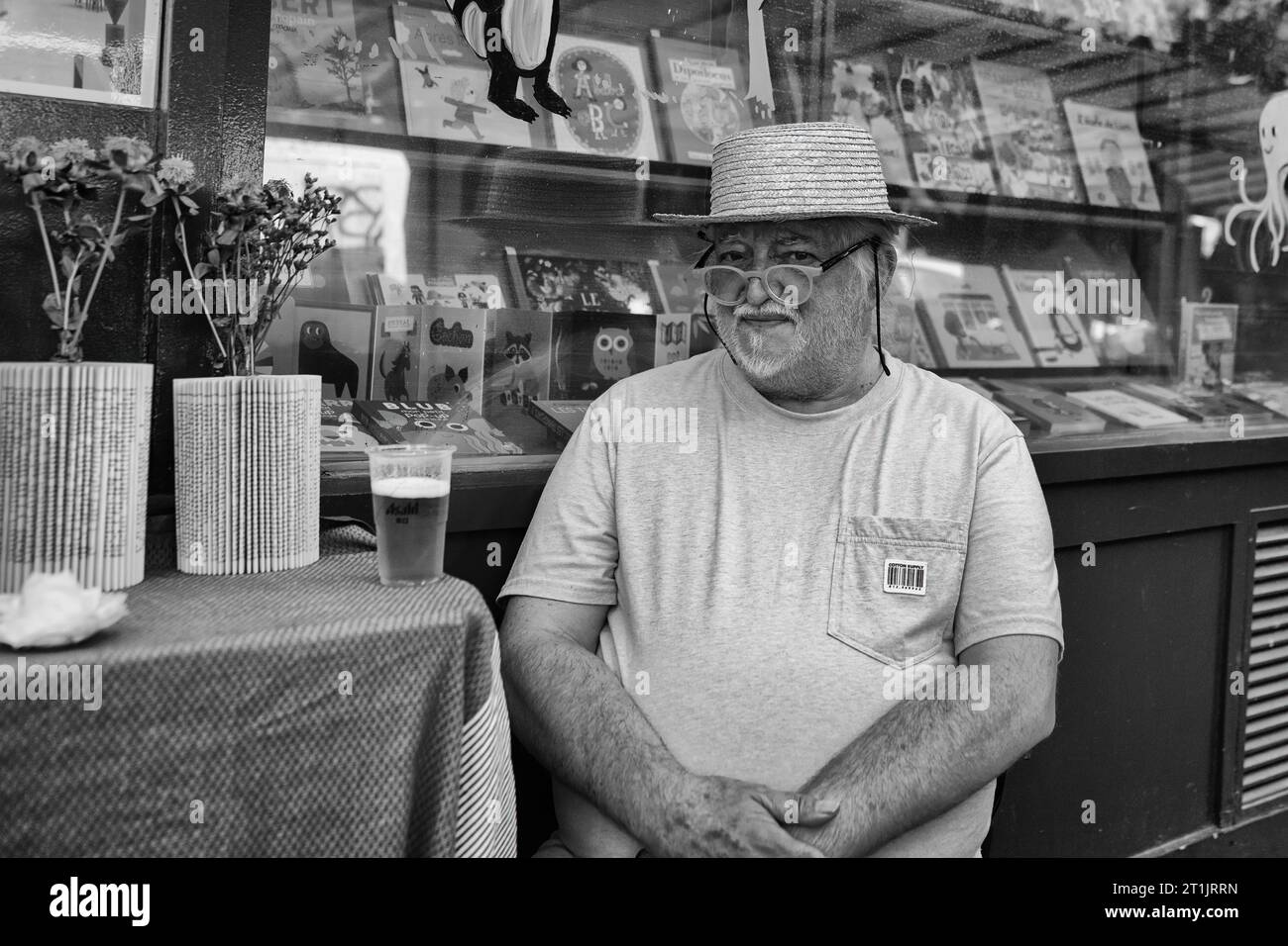 Patron sitzt auf der Straße vor einem lokalen Buchladen, Le Marais, Paris, Frankreich Stockfoto