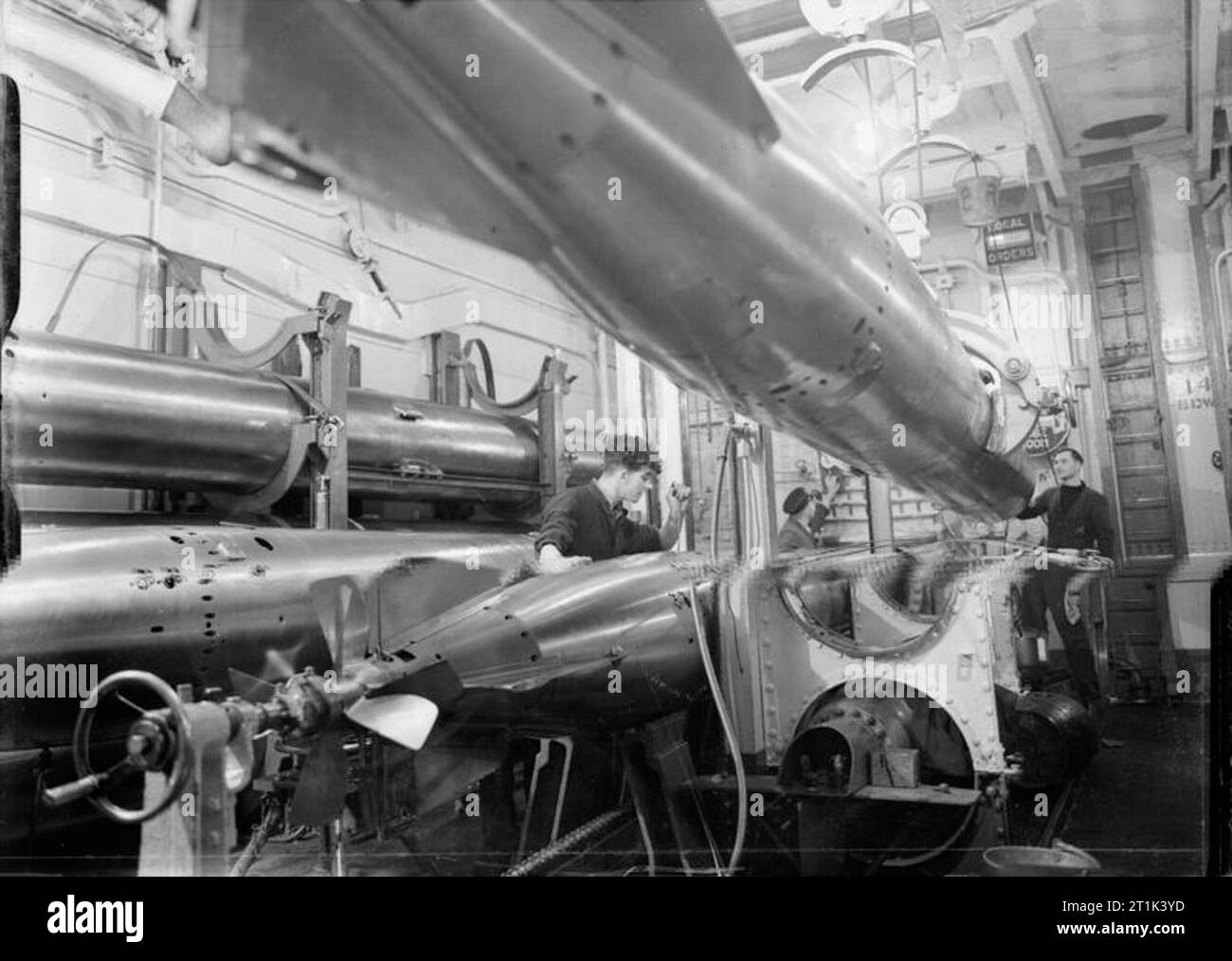 Die Royal Navy während des Zweiten Weltkriegs in diesem seltenen Blick auf die Torpedo Zimmer von HMS Rodney, einer Ihrer 24,5 cm Torpedorohre geladen wird. Ein weiteres wird abgesenkt auf die Keile torpedieren. Stockfoto