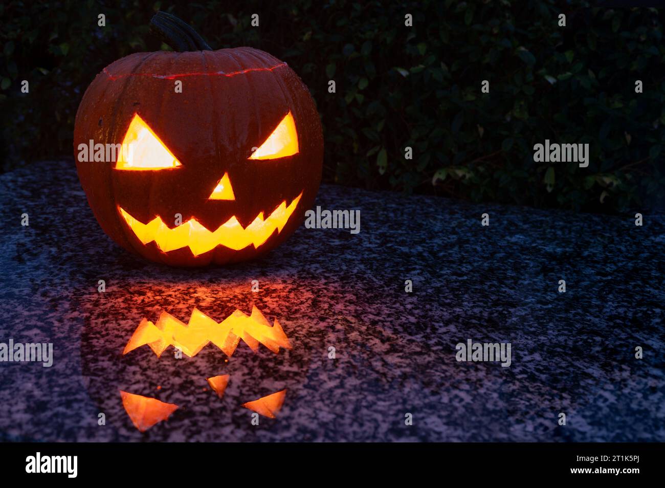 Hausgemachter und innen beleuchteter leuchtender Halloween-Kürbis mit geschnitztem Gesicht und gruseliger Erscheinung in der Dunkelheit Stockfoto