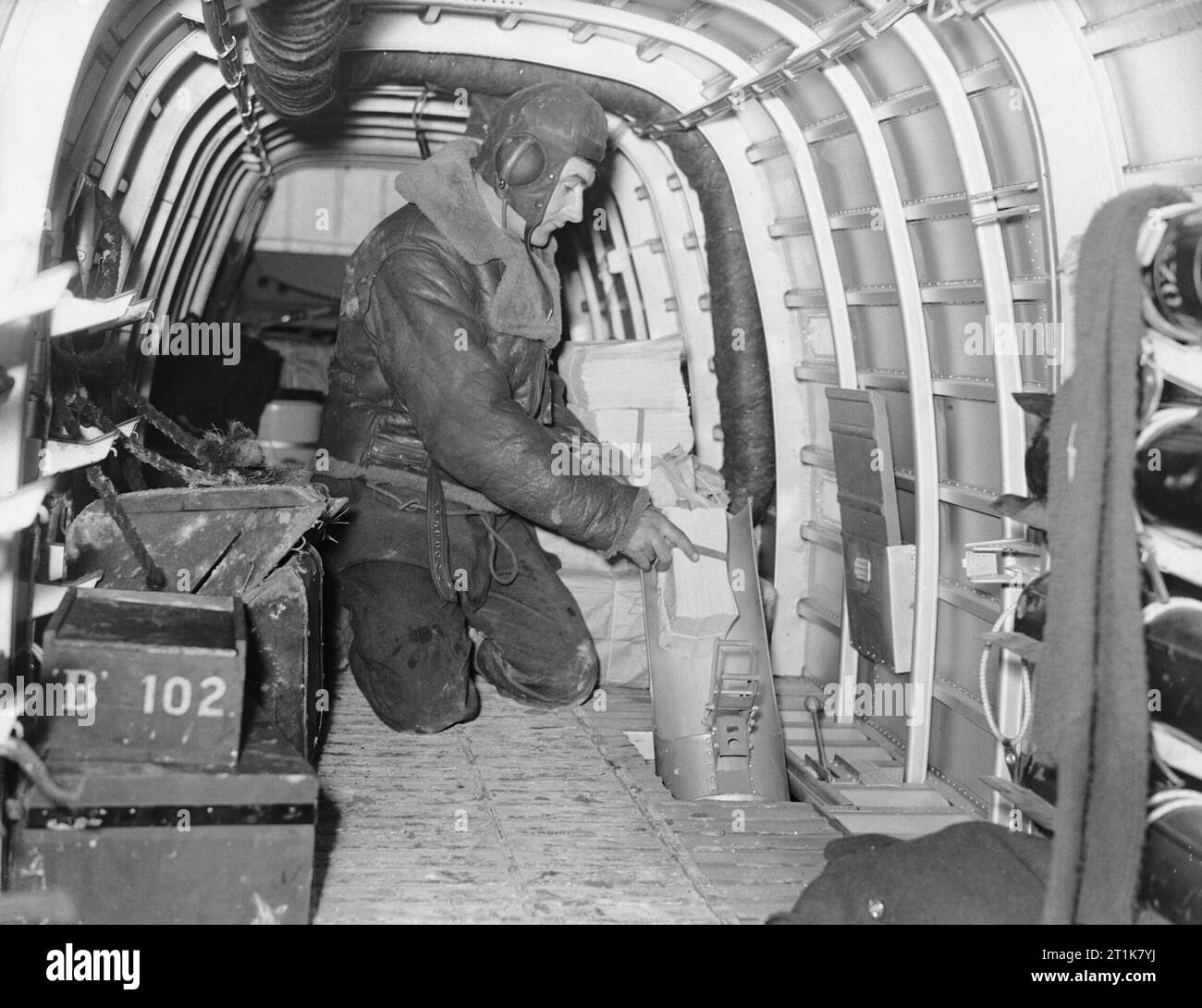 Royal Air Force Bomber Command, 1939-1941. Eine der Flugzeugbesatzung eines Armstrong Whitworth Whitley Mark V eines Nr. 102 Squadron RAF in Villeneuve/Vertus, Frankreich, zeigt auf, wie Propaganda Blättchen sind durch die flare Rutsche auf der Packungsbeilage fallengelassen - Fallenlassen ('Nickelling') Ausfällen. Stockfoto