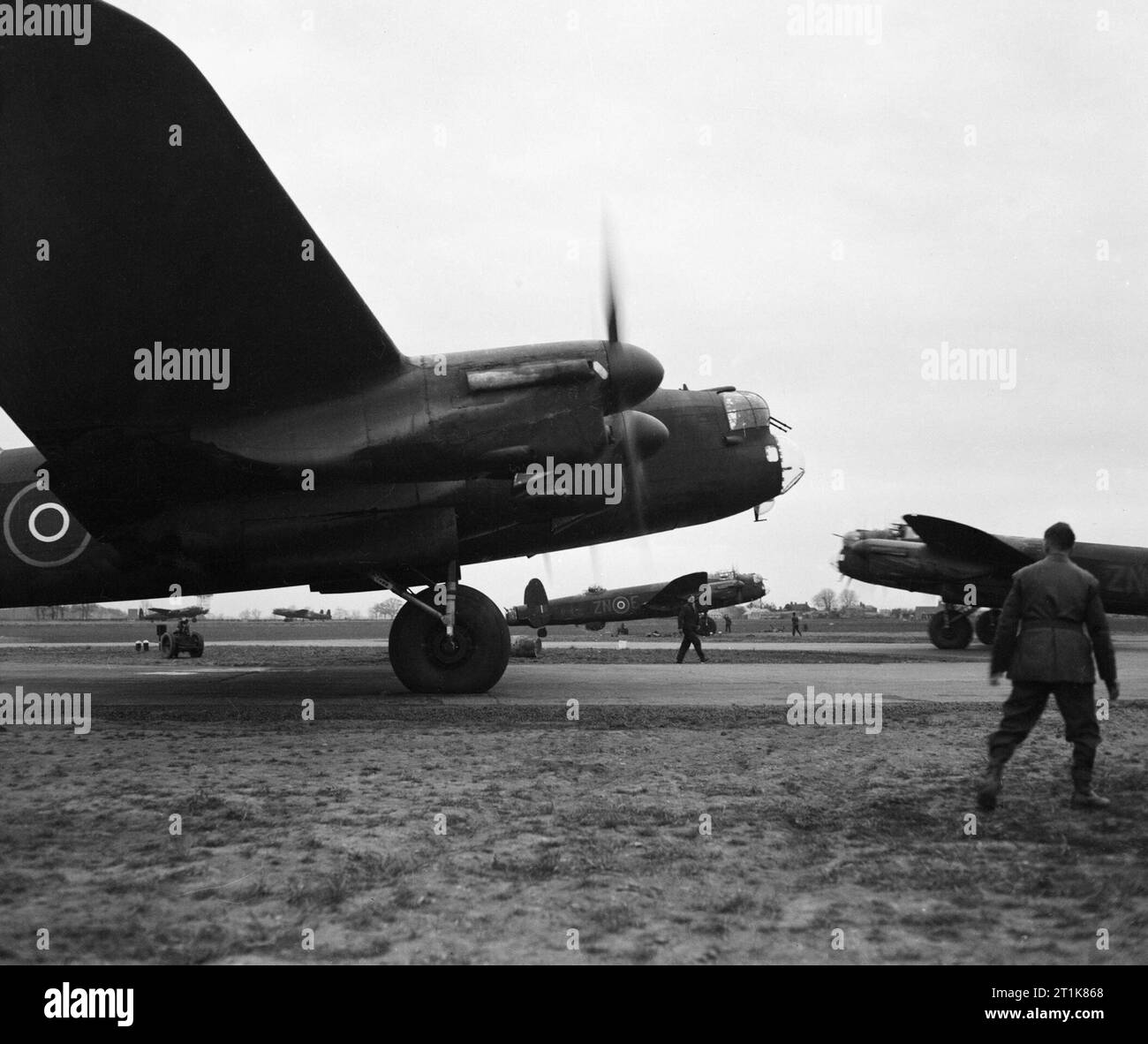 Royal Air Force Bomber Command, 1942-1945. Voll beladen, Avro Lancaster B Mark IIIs von Nr. 106 Squadron RAF taxy aus ihrer Verlegungen an den Kopf der Start- und Landebahn 20 an Metheringham, Lincolnshire, für Take-off auf einem Raid nach Frankfurt, Deutschland. Die daraus resultierende Angriff auf 22/23 März 1944 hervorgerufenen umfangreichen Zerstörung zu Ost-, Mittel- und westlichen Bezirken der Stadt, wie die Oper und die erhaltenen mittelalterlichen Viertel. Stockfoto