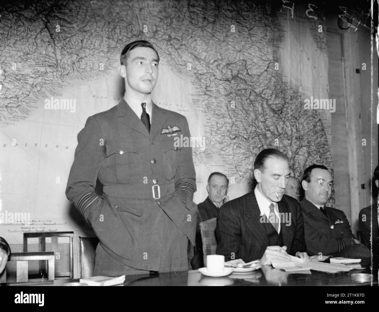 Royal Air Force Bomber Command, 1942-1945. Wing Commander J B 'Willy' Tait, Kommandierender Offizier der Nr. 617 Squadron RAF, gibt seinem Konto des erfolgreichen Raid auf das deutsche Schlachtschiff TIRPITZ in Tromsø, Norwegen Fjord (Katechismus) am 12. November 1944, während einer Pressekonferenz im Ministerium für Information, London. Saß neben Tait, in Zivil, ist Air Commodore H A Jones, Direktor für Öffentlichkeitsarbeit an der Luft Ministerium. Das Sitzen auf Jones' links ist Squadron Leader ein G Williams, der Nr. 9 Squadron RAF-Led auf dem Raid. Stockfoto