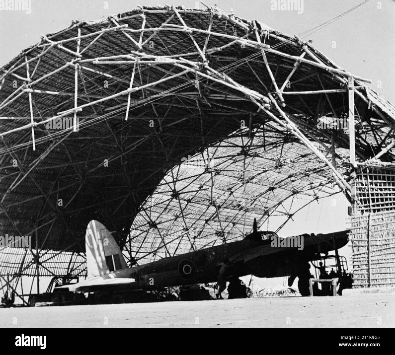 Royal Air Force im Nahen Osten, 1944-1945. Eine De Havilland Mosquito liegt geschützt in einem Hangar aus 'Barusti' (binsen und Zweige in eine offene Arbeit Muster gewebt) an Nr. 44 Staging Post, Sharjah, Trucial Staaten, während in den Fernen Osten Theater übergesetzt werden. Stockfoto