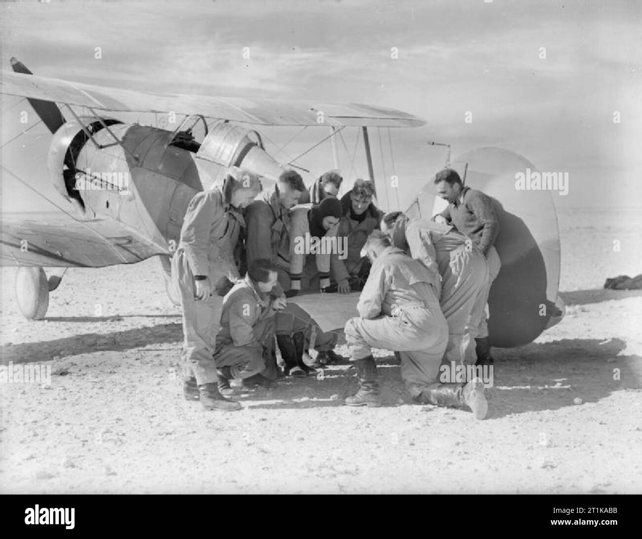 Royal Air Force Operationen im Nahen Osten und in Afrika, 1939-1943. Piloten von Nr. 3 Squadron RAAF Studie eine Karte auf das Höhenleitwerk eines ihrer Gloster Gladiator am Landeplatz in der Nähe von Sollum, Ägypten, bevor ein Betrieb über Bardia während der Schlussphase des Kompass. Nach rechts: Flying Offiziere J R Perrin J McD Davidson (Hocken) W S Arthur P ST G Turnbull Flug Leutnants G H Steege eine C Rawlinson Flying Officer V Ost (Unbekannt) Squadron Leader I D McLachlan (Kommandierender Offizier) Flying Officer A H Boyd Links Stockfoto