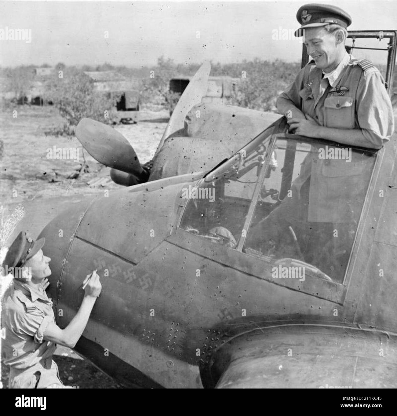 Royal Air Force - Italien, auf dem Balkan und in Südosteuropa, 1942-1945. Wing Commander C P 'paddy' Grün, Kommandierender Offizier der Nr. 600 Squadron RAF, Uhren aus dem Cockpit seiner Bristol Beaufighter Mark VIF bei Cassibile, Sizilien, als sein Radar operator, Flying Officer R J Gillies berührt die Hakenkreuze auf die Nase des Flugzeugs, Angabe der acht Siege, die sie behauptet hatte, während fliegen zusammen als "Night fighter Crew. Sieben dieser Siege wurden während drei aufeinanderfolgenden Nächten im Juli über Sizilien, vier von ihnen in einem einzigen Sortie erreicht. Grün hatte gerade die DSO für seine Fähigkeit ausgezeichnet. Stockfoto