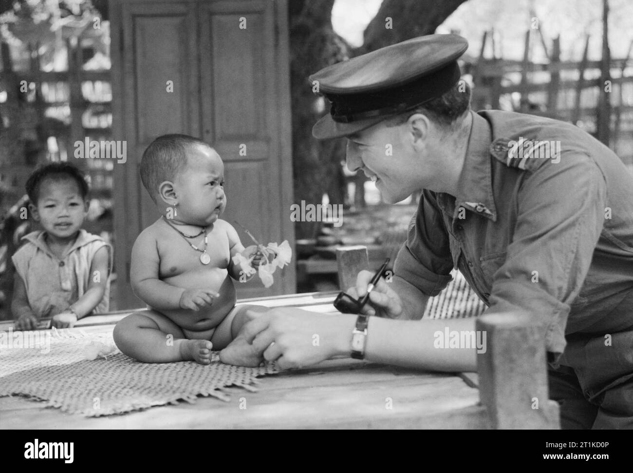 Squadron Leader Joseph Himmel, ein RAF methodistischen Kaplan, spielt mit einem Baby in einem Dorf in der Nähe von Monywa in Birma, März 1945. Squadron Leader Joseph Himmel, ein RAF methodistischen Kaplan von Bedford, spielen mit einer burmesischen Baby in einem Dorf in der Nähe von Monywa, wo er vierzig Burmesischen Christen, die aus der Methodistischen Mission und Schule bei Monywa evakuiert worden waren. Es war dort, dass er die erste Methodist Service in diesem Teil von Burma für drei Jahre statt. Stockfoto