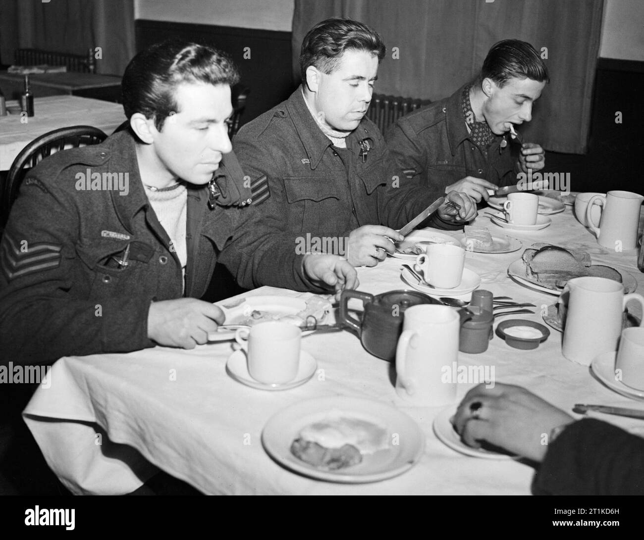 Die Besatzung eines Avro Lancaster der Nr. 57 Squadron RAF essen ihre Eier und Speck an Scampton, Lincolnshire, nach der Rückkehr von einem Raid, Februar 1943. Sergeant J B Mallett, Sergeant H H Turkentine und Sergeant R H P Roberts, Flugingenieur, Bombe aimer und Teamkollege, einer Avro Lancaster B Mark I Nr. 57 Squadron RAF, essen Frühstück in der Offiziersmesse Sergeants' an Scampton, Lincolnshire, die nach ihrer Rückkehr von einer Nacht-Raid. Alle drei wurden mit dem Rest der Crew von Lancaster R 5894 "DX-T" (T für Tommy'), wenn es kollidierte mit Zündkabel in der Nähe von Scampton nach Rückkehr getötet Stockfoto
