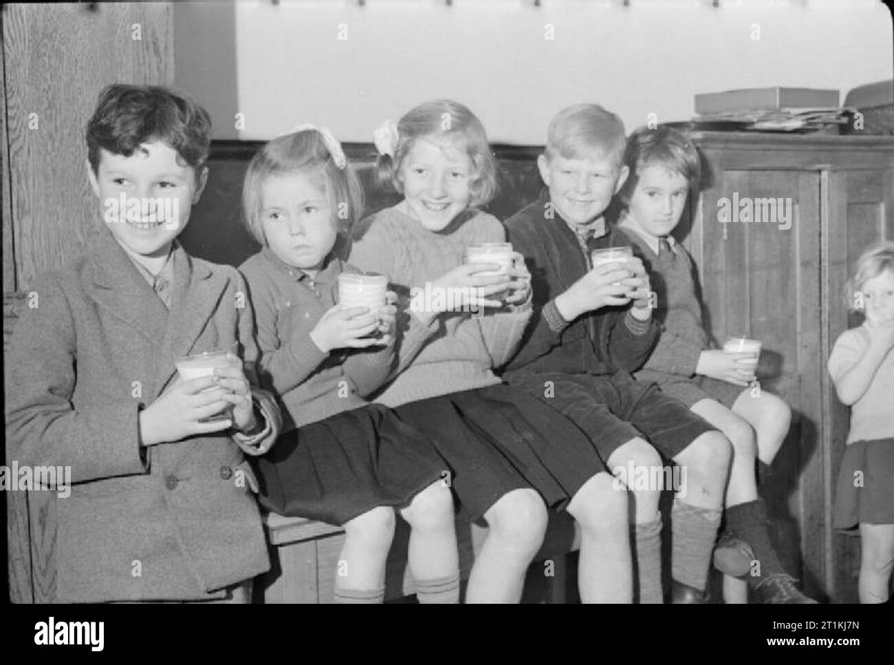 Chipstead Rat Schule - Bildung und kommunale Fütterung, Chipstead, Surrey, 1942 fünf Kinder ihr morgen Milch in einem Klassenzimmer an chipstead Rat Schule genießen. Von links nach rechts sind es: John Ramsden, Sheila Crouch, Una Trichter, Ronald Merritt und Malcolm Reade. Stockfoto