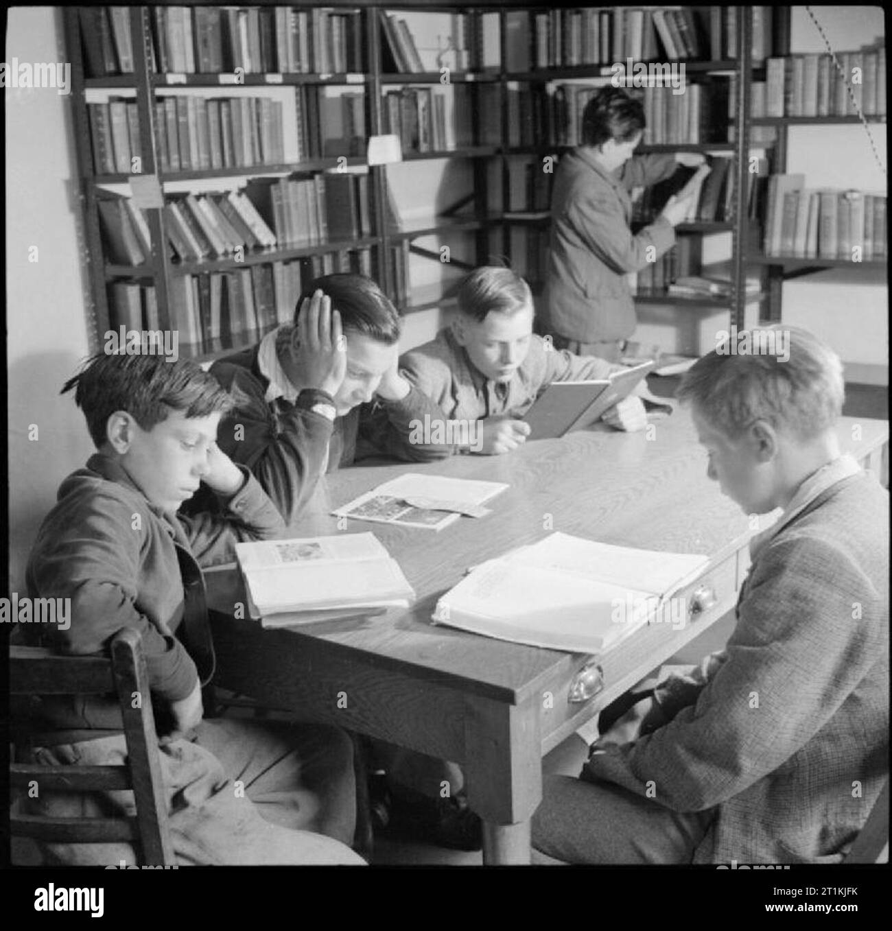 Land Schule - Alltag in Baldock County Council Schule, Baldock, Hertfordshire, England, UK, 1944 eine Gruppe von Jungen lesen Bücher in der Schulbibliothek in Baldock County Council Schule. Stockfoto
