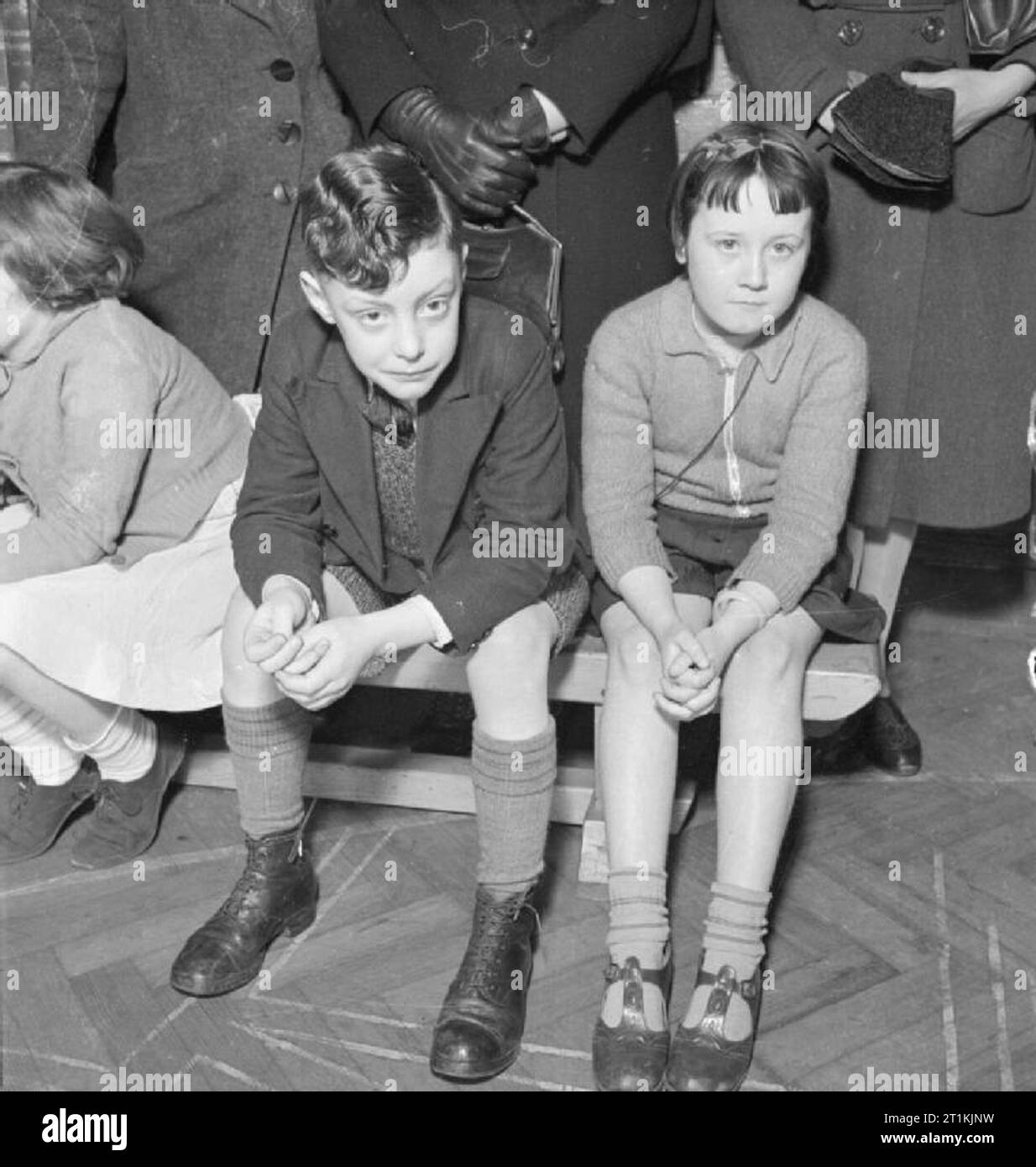 Diphtherie- Impfung Regelung, London, England, 1941 Ronald Ford (7 Jahre) und einem Freund auf einer Bank sitzen, die wiederum mit der Krankenschwester zu erwarten. Sie sind etwa gegen Diphtherie in Argyle Street School Klinik, 7. Mai 1941 immunisiert werden. Stockfoto