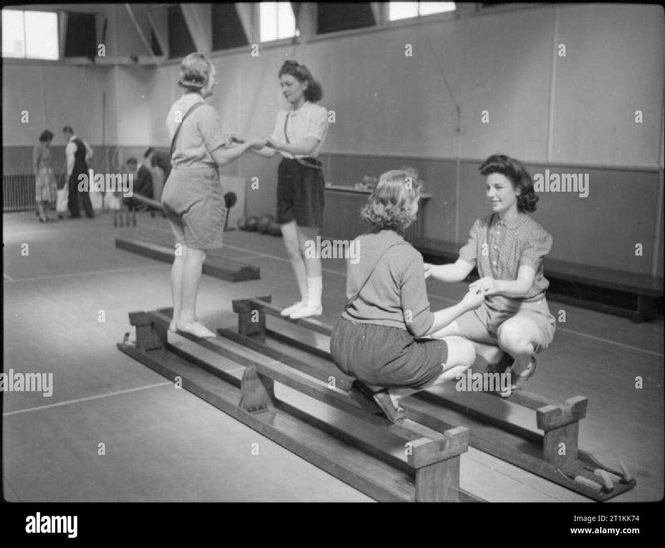 Werk wohl Arbeit - Wohlfahrt an die Pilkington Glass Factory, St Helens, Lancashire, England, Großbritannien, 1944 Frauen Balance auf umgedrehten Bänken in der Turnhalle an der Fabrik Rehabilitation Centre, (vermutlich auf der Pilkington Glas arbeitet bei St Helens), als Teil ihrer Erholung nach einer Verletzung. Nach dem ursprünglichen Titel' das Ziel der [center] ist, um Männer und Frauen aus dauerhaft deaktiviert zu verhindern. Durch Übungen und Massagen unter der Leitung des physio-Therapeuten in modernen Methoden der verletzten Personen erholsame Behandlung gegeben werden, bis sie die maximale Erholung von der Erreichung geschult Stockfoto