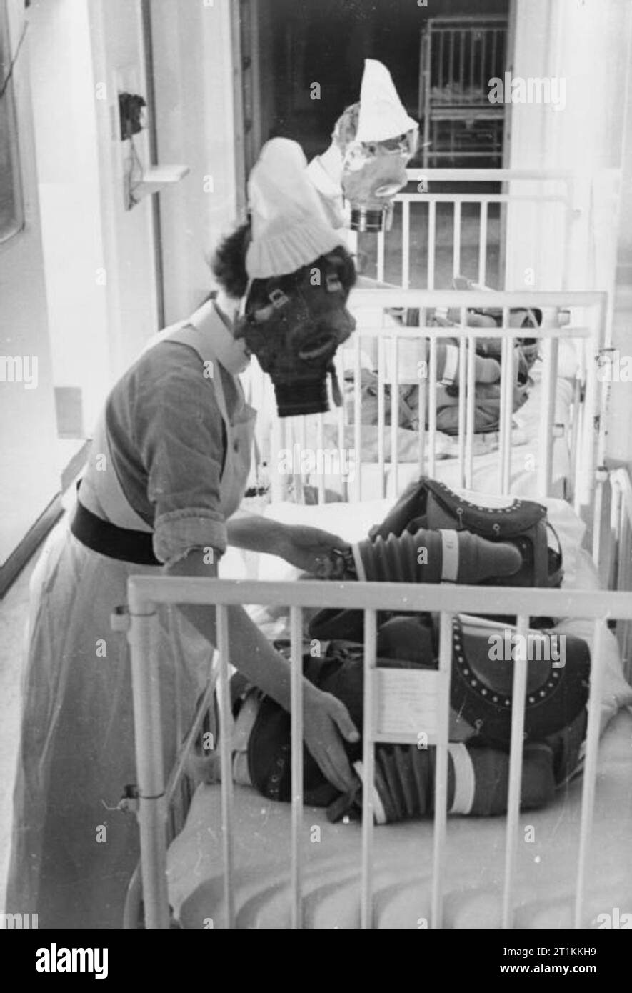 Gas Bohren in einem Londoner Krankenhaus - Gasmasken für Babys getestet, England, 1940 Zwei Krankenschwestern jede Pumpe der Balg eines Babys gas Atemschutzmaske, um das Kind zu versorgen das Tragen der Maske mit Luft, während ein Gas bohren in einem Londoner Krankenhaus, 1940. Stockfoto