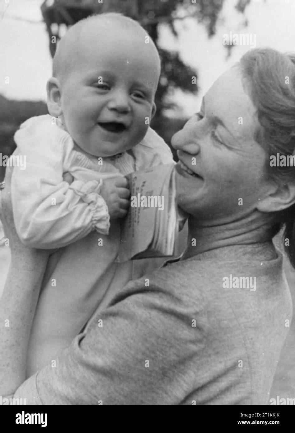 A Village Saves- National Savings in Lewknor, Oxfordshire, England, 1941 Ein Porträt eines lächelnden John Andrew, im Alter von 6 Monaten, mit seiner Mutter. John ist sein Gewicht in Gold Wert, da er 18 Pfund wiegt und über nationale Sparzertifikate im Wert von 18 Pfund verfügt. Stockfoto