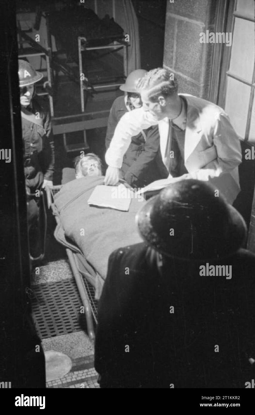 Guy's Hospital - Leben in einem Londoner Krankenhaus, England, 1941 Der Arzt als "Tally" nimmt den Unfall auf der MPC 47 Form, die den Unfall während Ihrer Behandlung begleiten. Der tally Mann stellt das Dokument auf der Bahre mit der Unfall vor dem Stretcher - Träger des Patienten in das Krankenhaus. Stockfoto