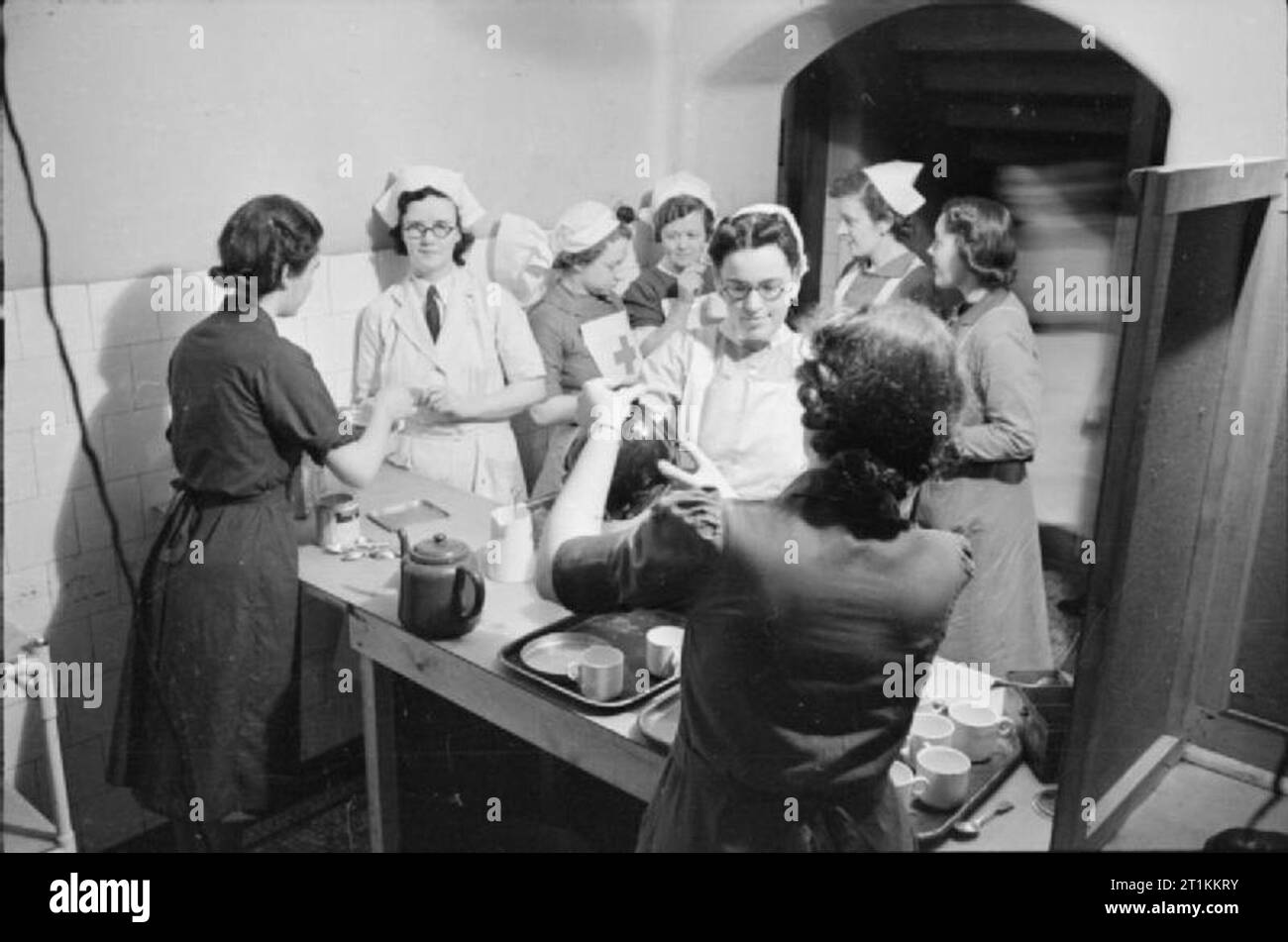 Guy's Hospital - Leben in einem Londoner Krankenhaus, England, 1941 eine Gruppe von Krankenschwestern an Guy's Hospital in London erhalten Tassen Kaffee aus der Kantine, goß für sie kaufen Mitglieder der freiwilligen Dienst der Frauen (WVS). Es gibt verschiedene Arten von Krankenschwestern bei der Arbeit an der Kerl ist, einschließlich VADs (freiwillige Hilfe Loslösung Krankenschwestern), und jene, die aus dem roten Kreuz. Stockfoto